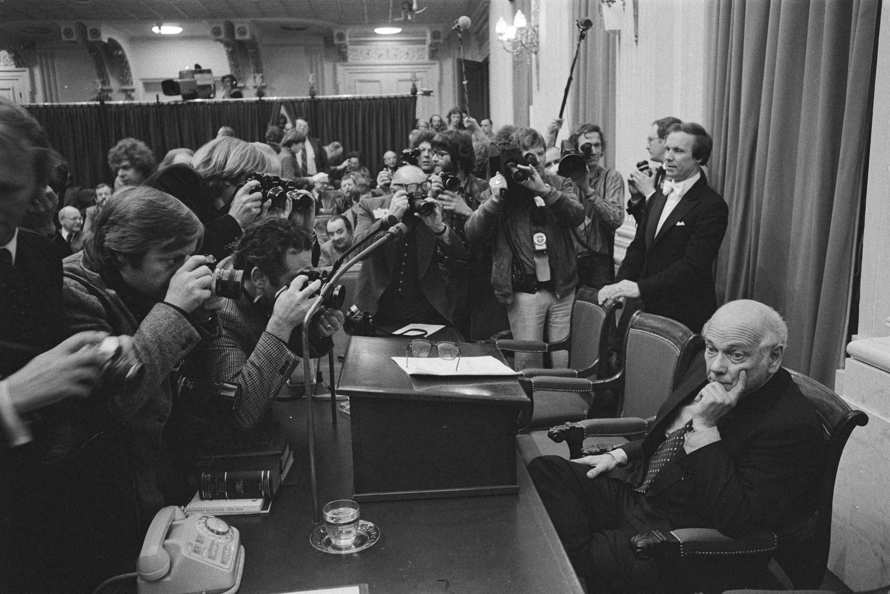 Regeringsverklaring: Val kabinet Den Uyl — Premier Den Uyl (niet zichtbaar) wordt belaagd door fotografen in de Tweede Kamer — Foto: Verhoeff, Bert / Anefo. Licentie: Set B: Rechtenvrij / Publiek Domein. Bron: Nationaal Archief. http://hdl.handle.net/10648/ac981746-d0b4-102d-bcf8-003048976d84