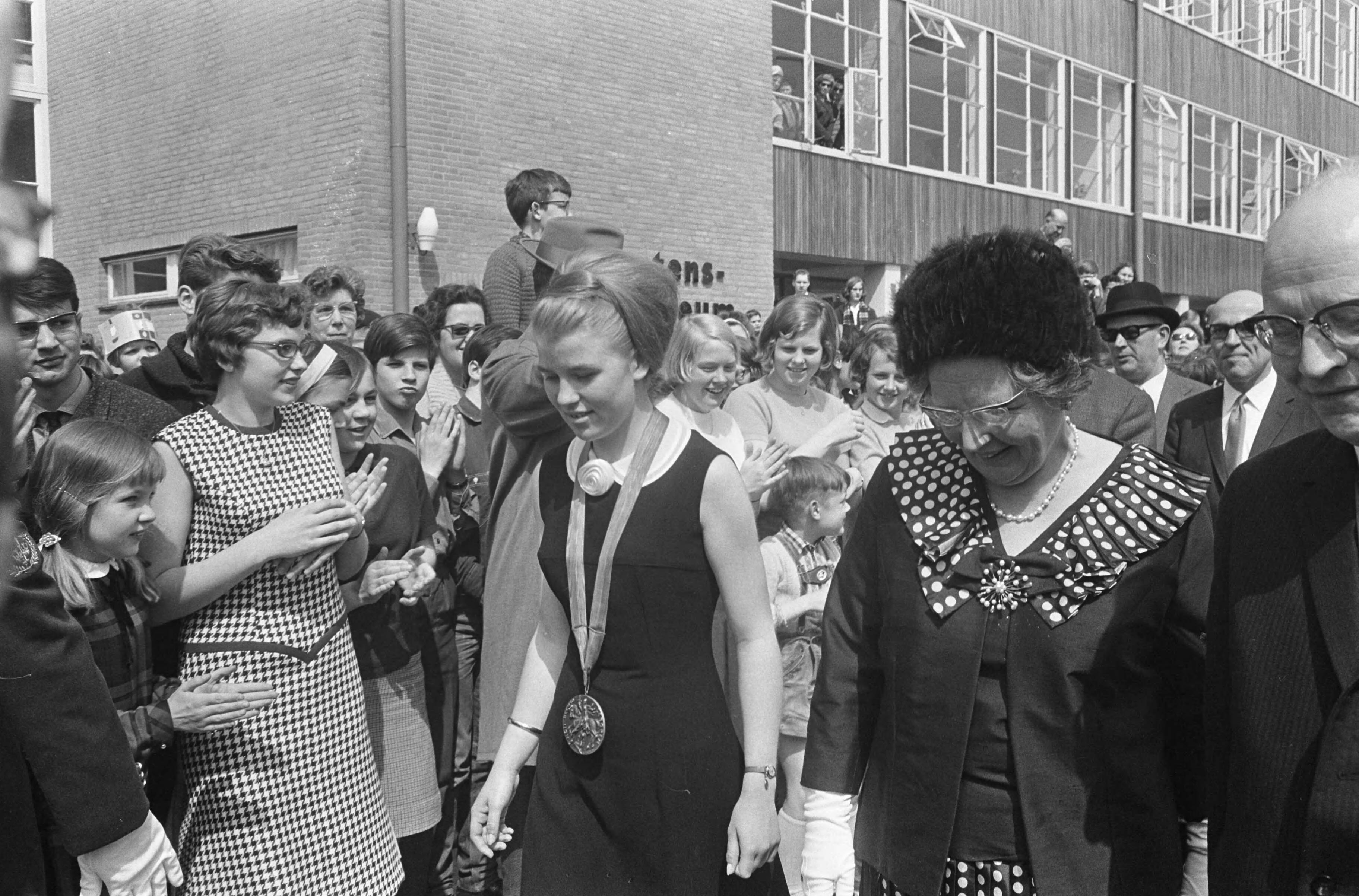 Fotocollectie Anefo — Koningin Juliana in Voorburg, Opening St. Maartenslyceum. De koningin loopt door een haag van scholieren — Foto: Koch, Eric / Anefo. Licentie: Set B: Rechtenvrij / Publiek Domein. Bron: Nationaal Archief. http://hdl.handle.net/10648/aae74872-d0b4-102d-bcf8-003048976d84