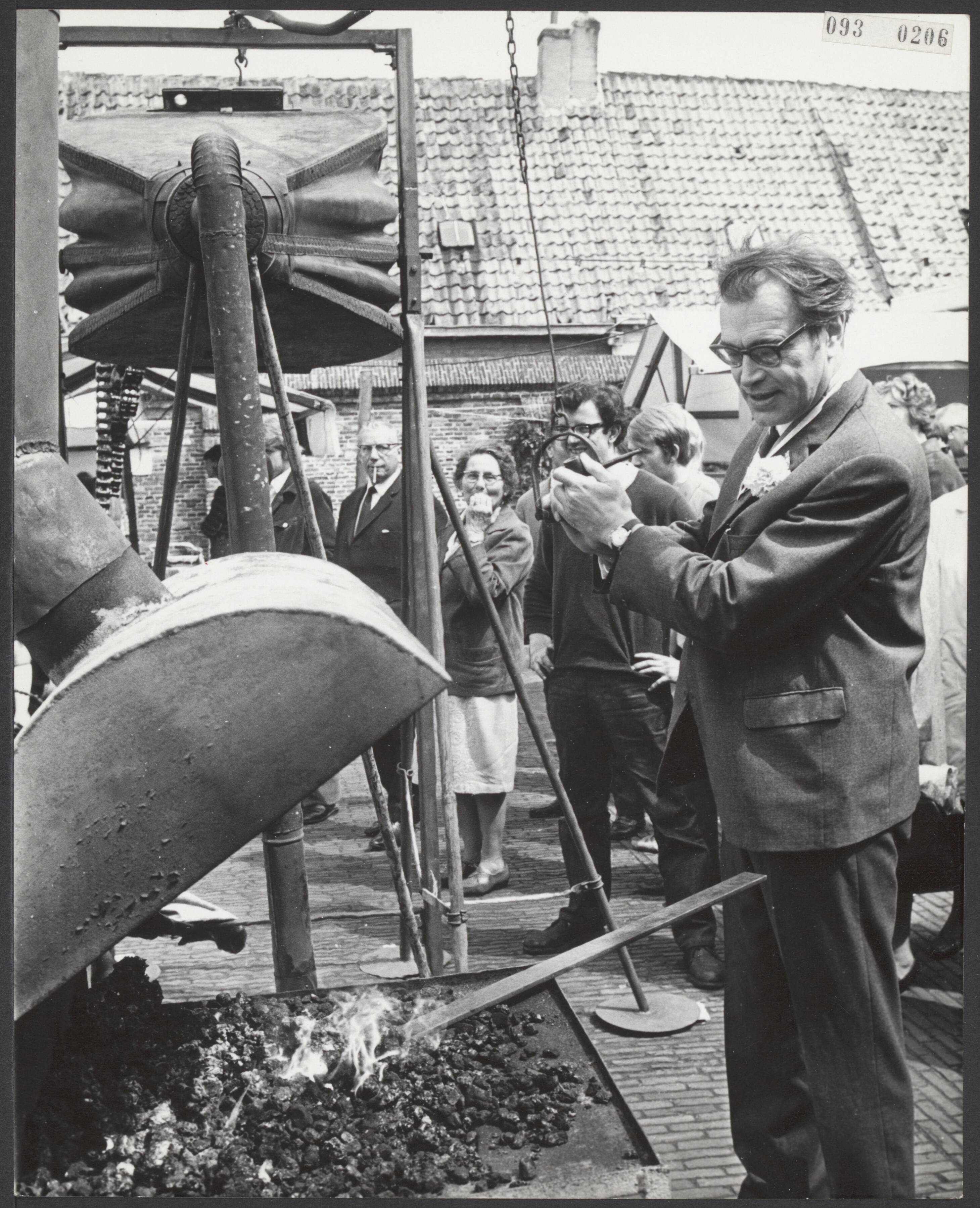 Fotocollectie Elsevier Binnenland — Op de Haarlemse Botermarkt heeft de schrijver Godfried Bomans de 5e Kunstmarkt geopend. Het was ook de vijfde keer dat hij dit mocht doen. Een belangrijk deel van de opbrengst is bestemd voor het gehandicapte kind in Haarlem en omgeving. Na een korte openingsrede hielp Godfried Bomans de siersmid op de markt met het aanwakkeren van het vuur door middel van een grote blaasgalg, waarna kunstenaars aan het werk gingen. — Foto: Koch, Eric / Anefo. Licentie: Set B: Rechtenvrij / Publiek Domein. Bron: Nationaal Archief. http://hdl.handle.net/10648/ae27782c-d0b4-102d-bcf8-003048976d84