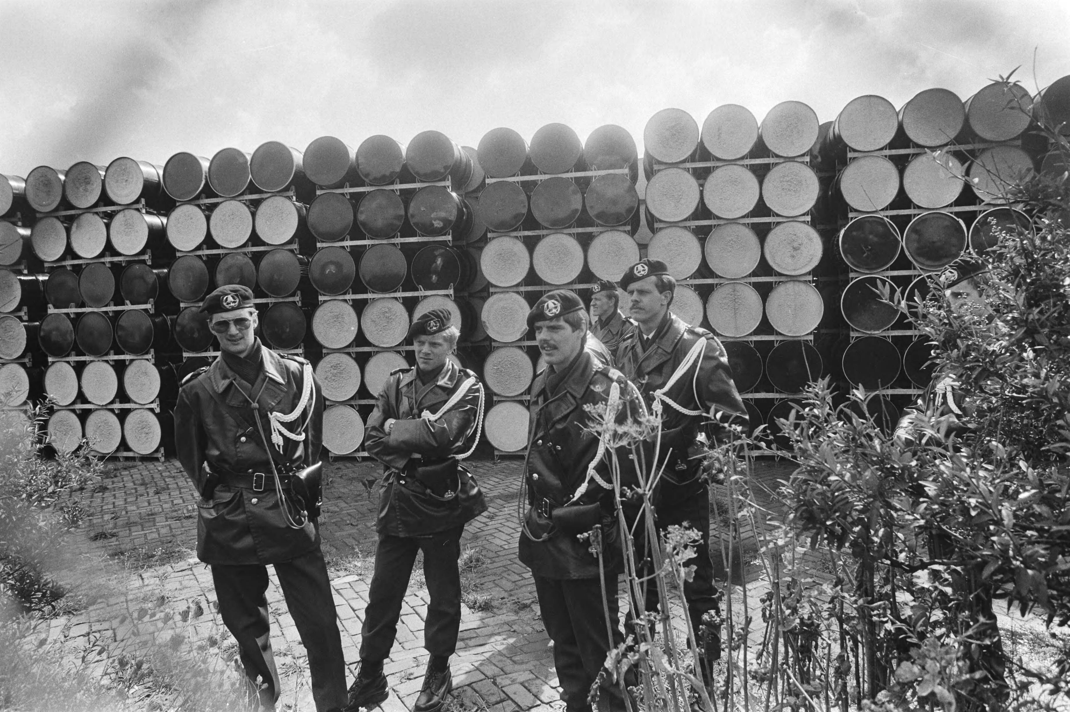 Fotocollectie Anefo — Akties tegen transport radioactief afval van Petten naar Den Helder ; marechaussee bewaakt de opgeslagen vaten — Foto: Dijk, Hans van / Anefo. Licentie: Set B: Rechtenvrij / Publiek Domein. Bron: Nationaal Archief. http://hdl.handle.net/10648/ad1cea98-d0b4-102d-bcf8-003048976d84