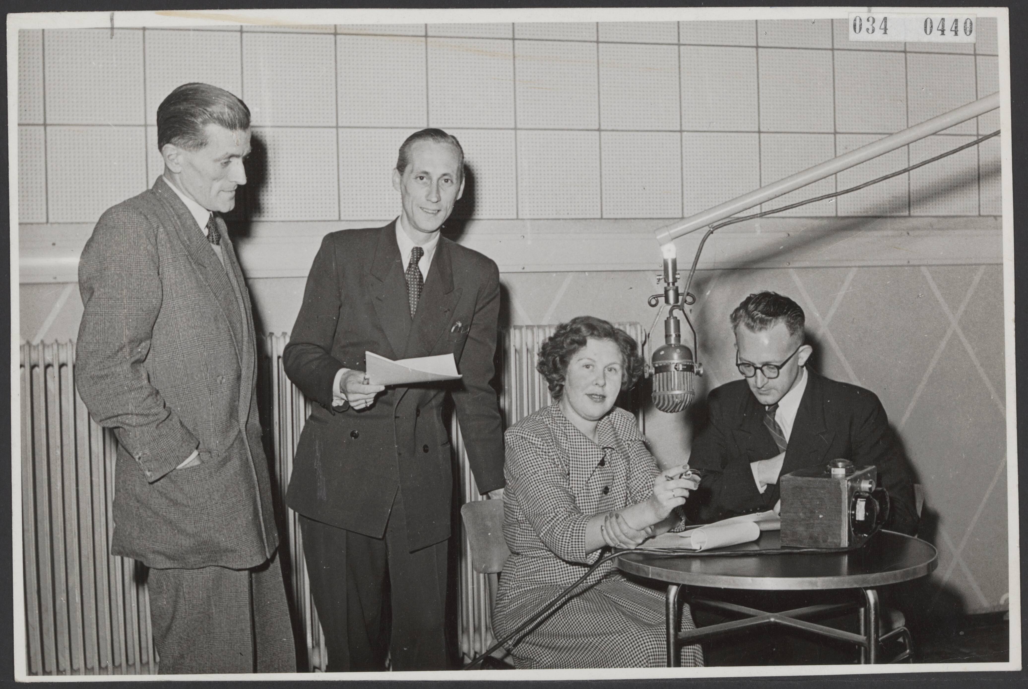 Fotocollectie Elsevier Binnenland — Team van de radioquiz " Hersengymnastiek " van de AVRO. Vlnr. Gerard van Krevelen (pianist), Jan Boots, Mieke (" hoe is de stand? ") Melcher en Jan van Herpen. Op de tafel staat het bekende zoemertje — Foto: Renes, Studio. Licentie: Set B: Rechtenvrij / Publiek Domein. Bron: Nationaal Archief. http://hdl.handle.net/10648/ade7ce2a-d0b4-102d-bcf8-003048976d84