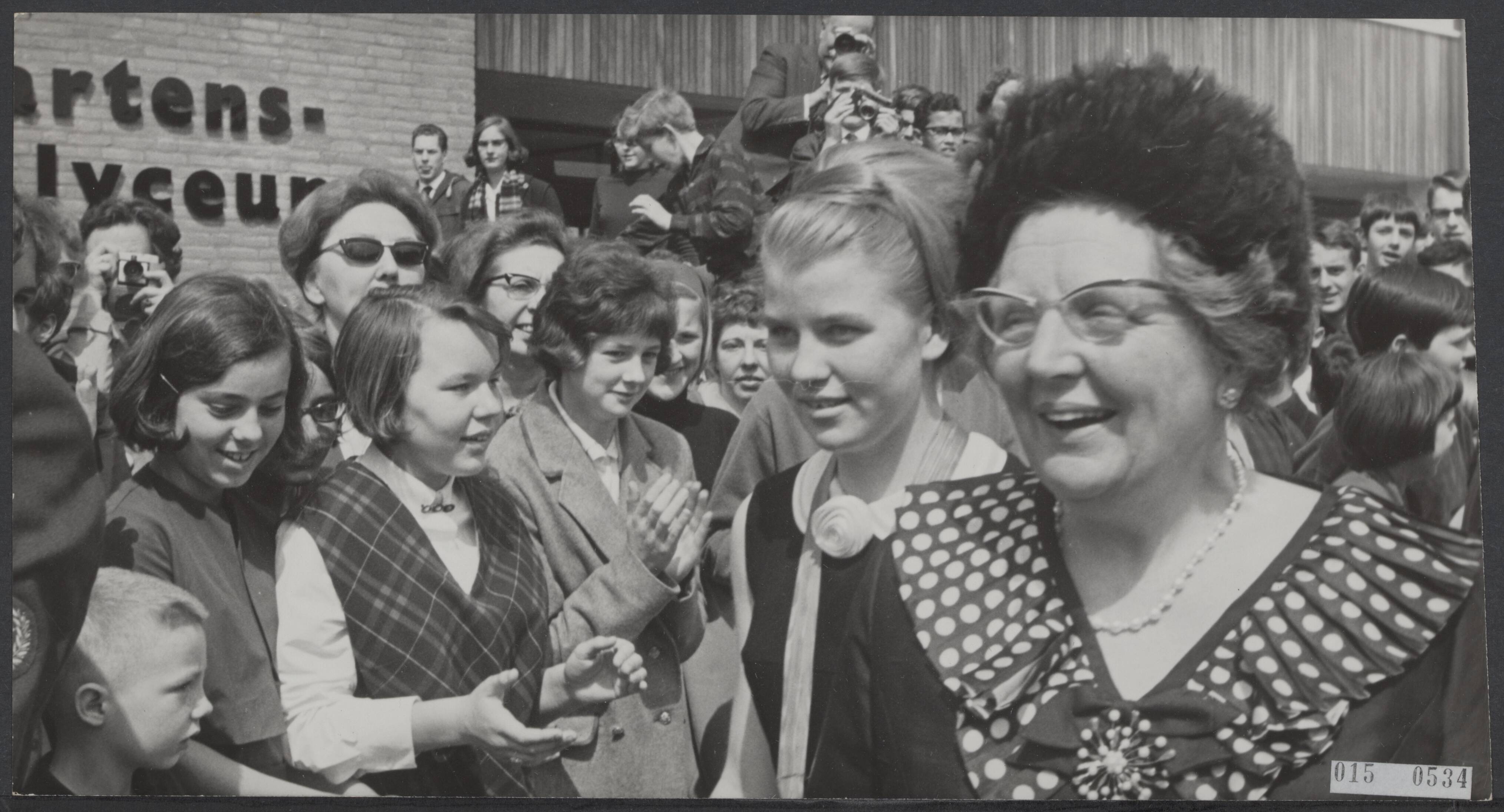 Fotocollectie Elsevier Binnenland — Koningin Juliana bracht een bezoek aan de gemeente Voorburg. Op het programma stond ook een bezoek aan het nieuwe Sint Maartenslyceum. Begeleid door de voorzitter van de leerlingen vereniging Leny van Haaster (links) liep de koningin door een haag van scholieren — Foto: Koch, Eric / Anefo. Licentie: Set B: Rechtenvrij / Publiek Domein. Bron: Nationaal Archief. http://hdl.handle.net/10648/adb55ed6-d0b4-102d-bcf8-003048976d84