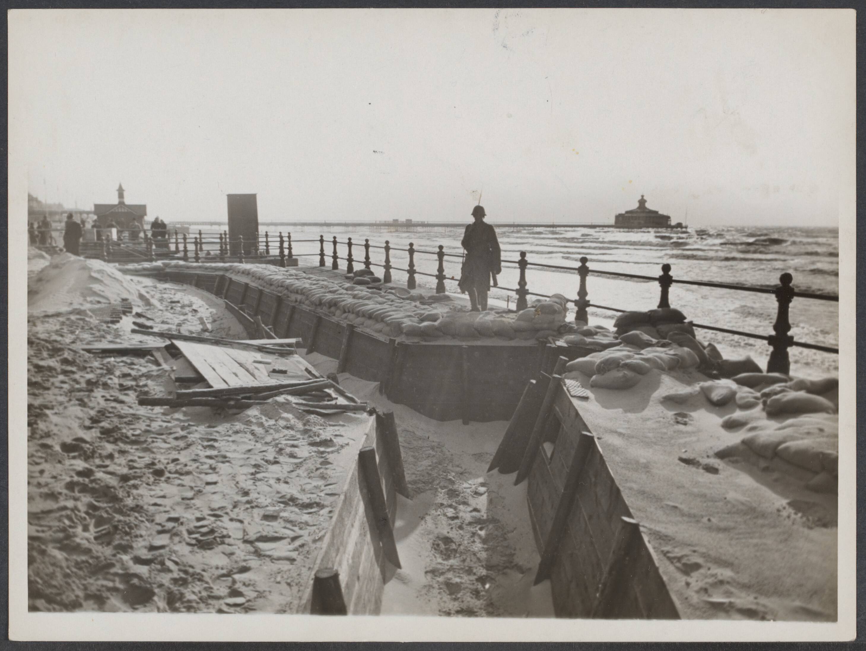Mobilisatie; voorgeschiedenis W.O.II enz. - Nederland — 1e Legercorps [loopgraven aan het strand van Scheveningen. In de achtergrond de Pier] — Foto: N.V. Vereenigde Fotobureaux. Licentie: Set B: Rechtenvrij / Publiek Domein. Bron: Nationaal Archief. http://hdl.handle.net/10648/680f3c08-748f-22c1-3360-9d7ed3edda64