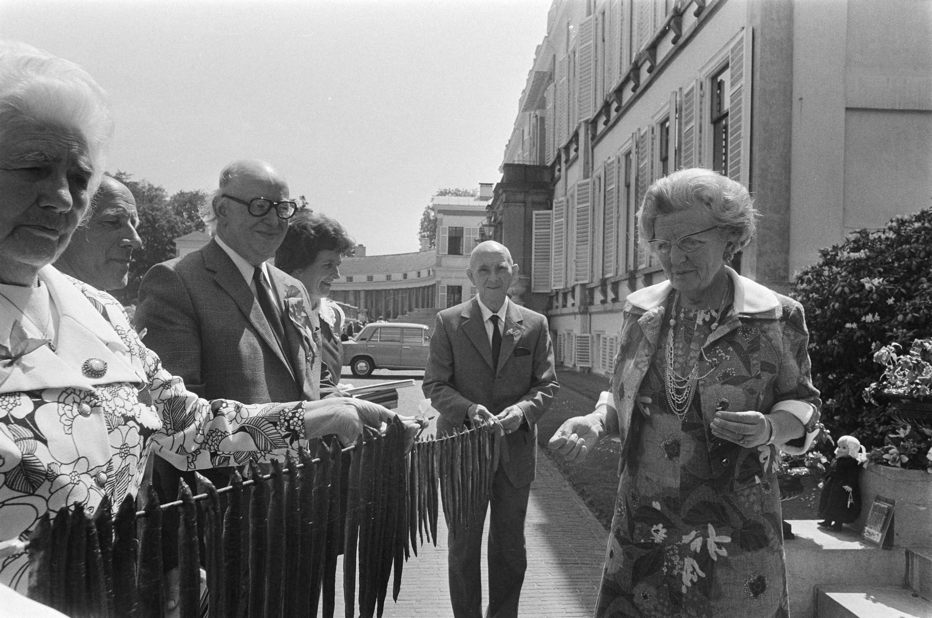 Bejaardendefilé op Paleis Soestdijk — Koningin Juliana krijgt paling uit Monnickendam aangeboden — Foto: Fotograaf Onbekend / Anefo. Licentie: Set B: Rechtenvrij / Publiek Domein. Bron: Nationaal Archief. http://hdl.handle.net/10648/ac4ca6bc-d0b4-102d-bcf8-003048976d84