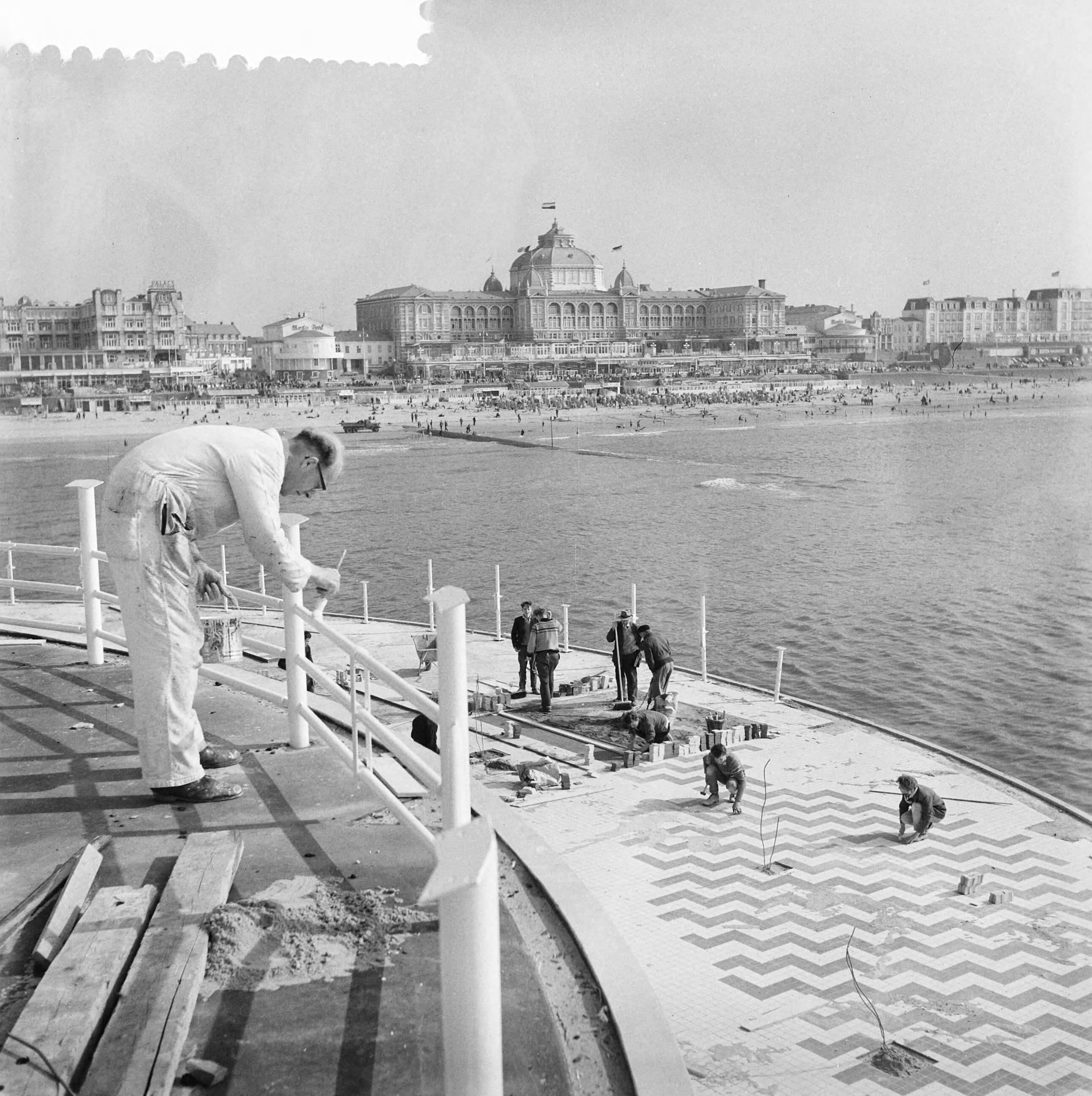 Fotocollectie Anefo — Werkzaamheden pier te Scheveningen. Schilderen van restaurant en wegen betegelen — Foto: Nijs, Jac. de / Anefo. Licentie: Set B: Rechtenvrij / Publiek Domein. Bron: Nationaal Archief. http://hdl.handle.net/10648/ad792e3e-d0b4-102d-bcf8-003048976d84