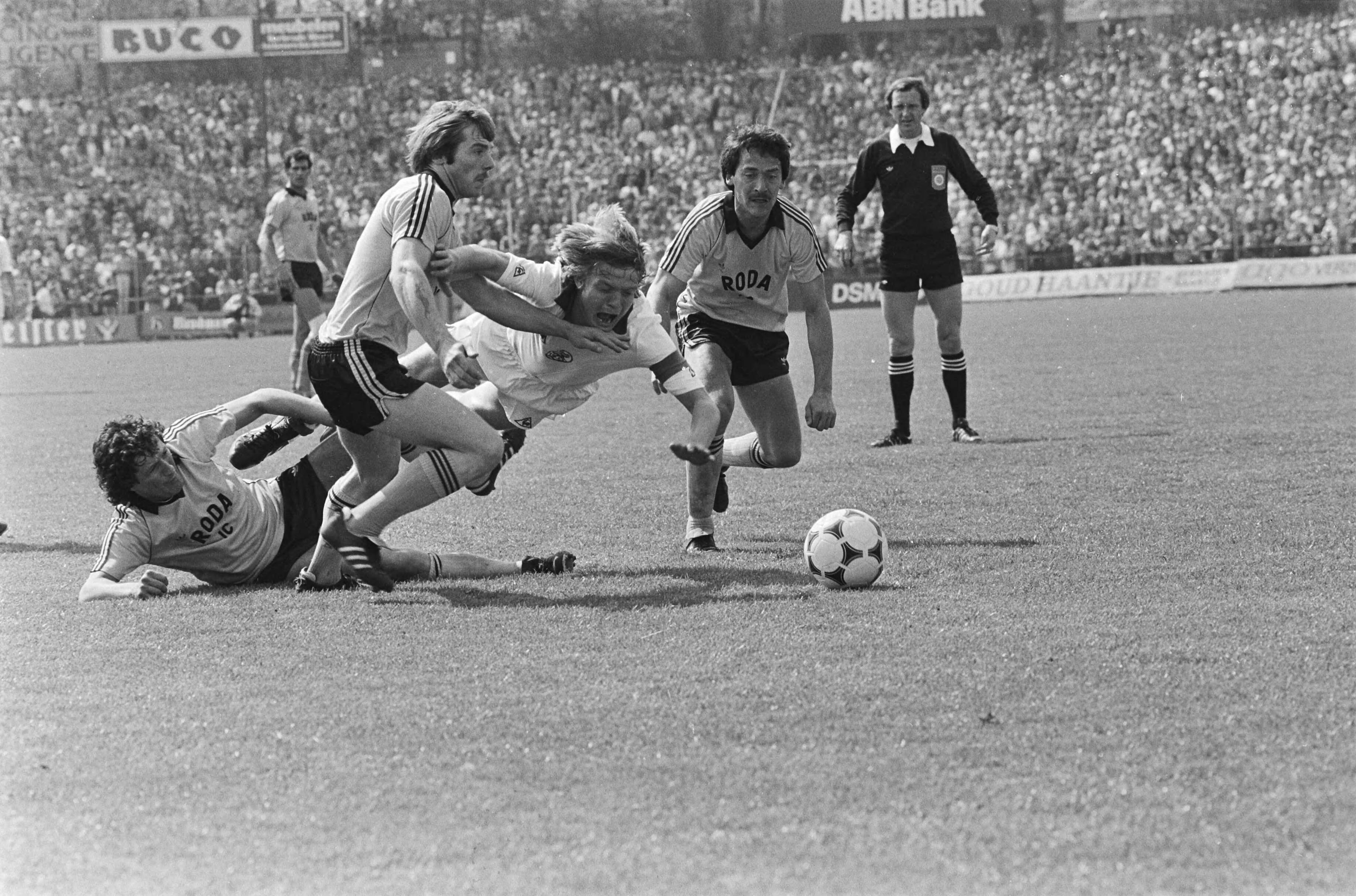 Fotocollectie Anefo — Roda JC tegen Ajax 1-1; Soren Lerby wordt ten val gebracht door v.l.n.r. Ehlen, Eugene Hanssen, Lerby en Marijnissen (van Roda), Bakker (scheidsrechter) kijkt toe (r) — Foto: Antonisse, Marcel / Anefo. Licentie: Set B: Rechtenvrij / Publiek Domein. Bron: Nationaal Archief. http://hdl.handle.net/10648/ad171a8c-d0b4-102d-bcf8-003048976d84