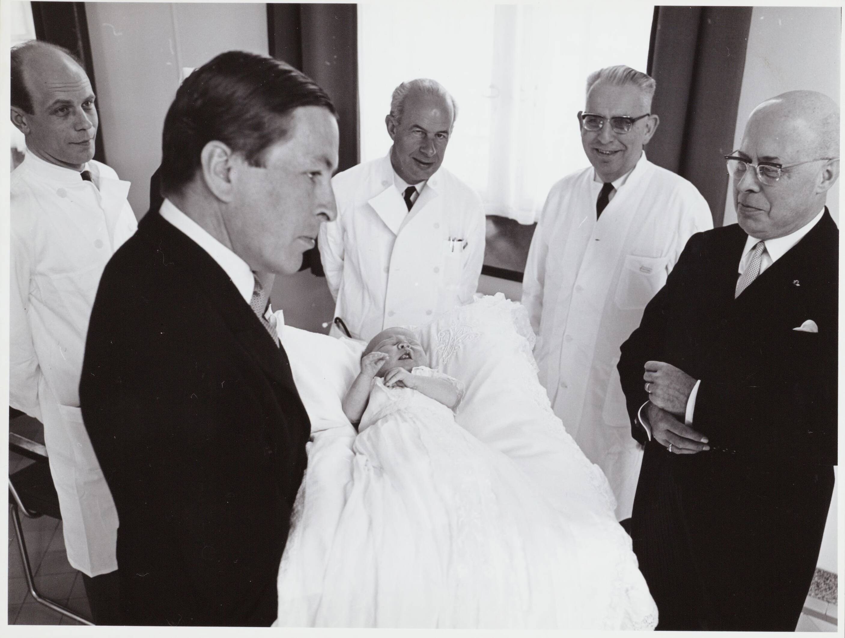Fotocollectie RVD / Koninklijk Huis — Prins Claus toont de baby prins Willem-Alexander aan de doktoren in het Academisch Ziekenhuis Utrecht op 2 mei 1967 — Foto: Nationaal Foto Persbureau / RVD. Licentie: Set B: Rechtenvrij / Publiek Domein. Bron: Nationaal Archief. http://hdl.handle.net/10648/afaf29a6-d0b4-102d-bcf8-003048976d84