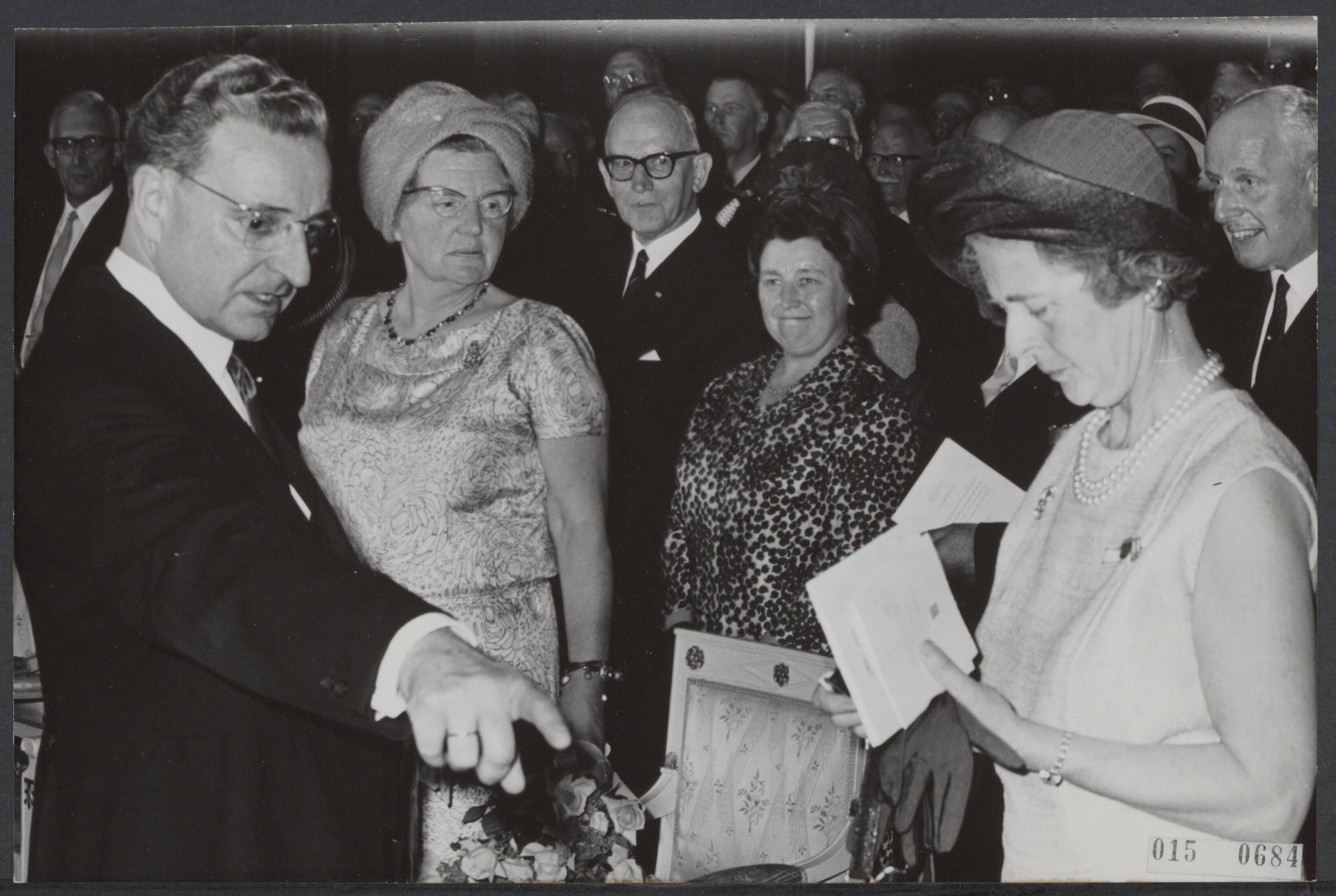 Fotocollectie Elsevier Binnenland — Paniek in de schouwburgzaal van Maastricht waar de herdenking plaatsvond t.g.v. de beëindiging van het lidmaatscvhap van het hertogdom Limburg van de Duitse Bond in aanwezigheid van koningin Juliana. Toen de hoge gasten hun plaatsen wilden innemen bleek voor minsiter Beel geen stoel gereserveerd te zijn, waardoor de hoge gasten alle naamkaartjes op de stoelen gingen controleren en de Commissaris der Koningin van Limburg, Ch. J.M.A. van Rooy op de vele stoelen wees en vroeg wie daar zat — Foto: Nijs, Jac. de / Anefo. Licentie: Set B: Rechtenvrij / Publiek Domein. Bron: Nationaal Archief. http://hdl.handle.net/10648/adb5d28a-d0b4-102d-bcf8-003048976d84