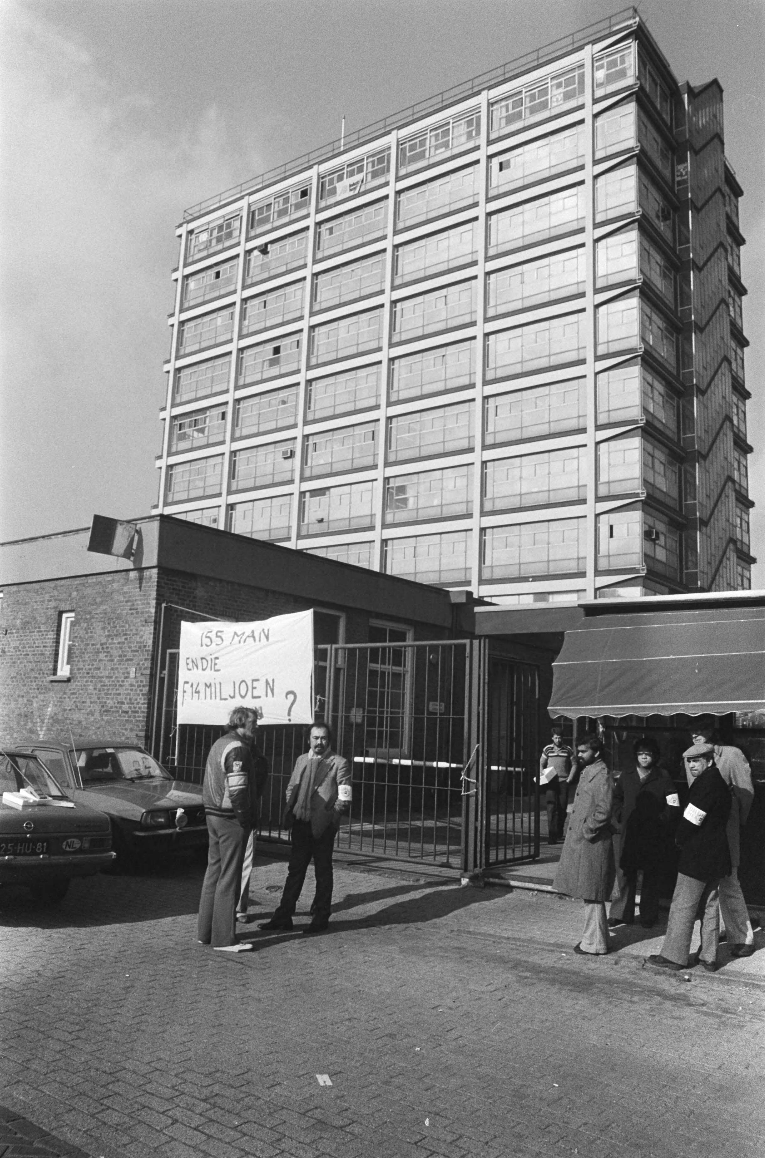 Nederlandsche Standard Electric Mij in Den Haag bezet door personeel — Bezetters voor de poort met spandoeken — Foto: Bogaerts, Rob / Anefo. Licentie: Set B: Rechtenvrij / Publiek Domein. Bron: Nationaal Archief. http://hdl.handle.net/10648/acc5f260-d0b4-102d-bcf8-003048976d84