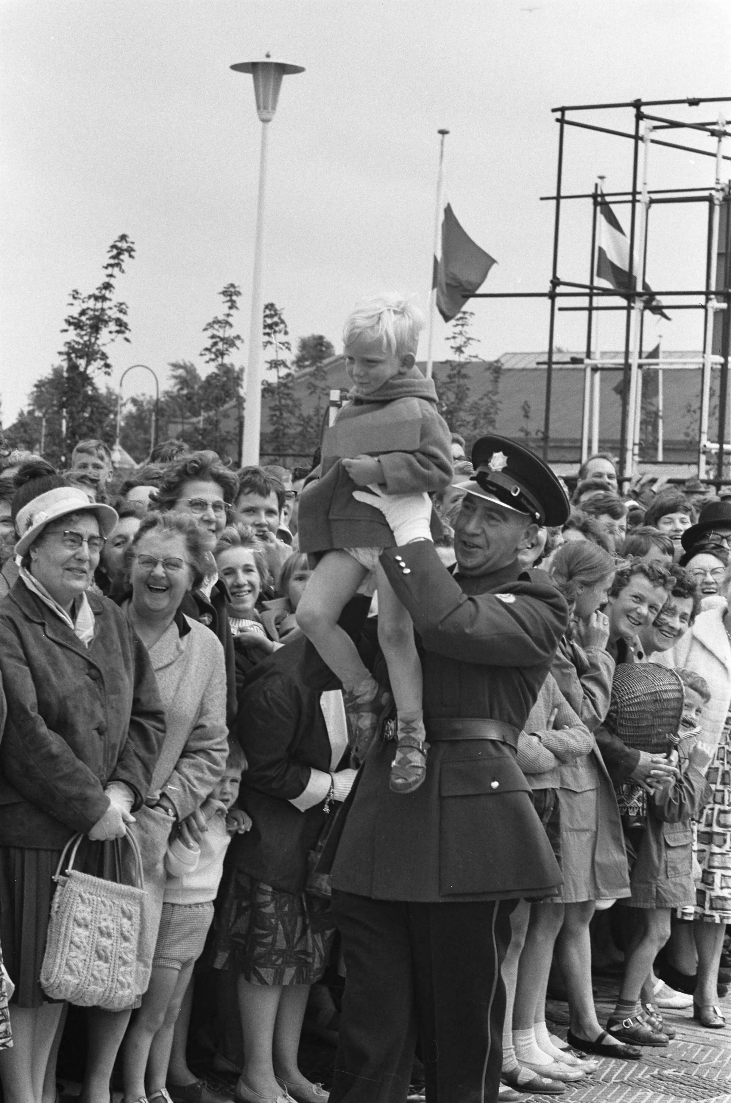 Fotocollectie Anefo — Koningin Juliana bezoekt tentoonstelling "Nu .... Breda 61 ". Agent draagt jongetje weg — Foto: Pot, Harry / Anefo. Licentie: Set B: Rechtenvrij / Publiek Domein. Bron: Nationaal Archief. http://hdl.handle.net/10648/a9dd1d12-d0b4-102d-bcf8-003048976d84