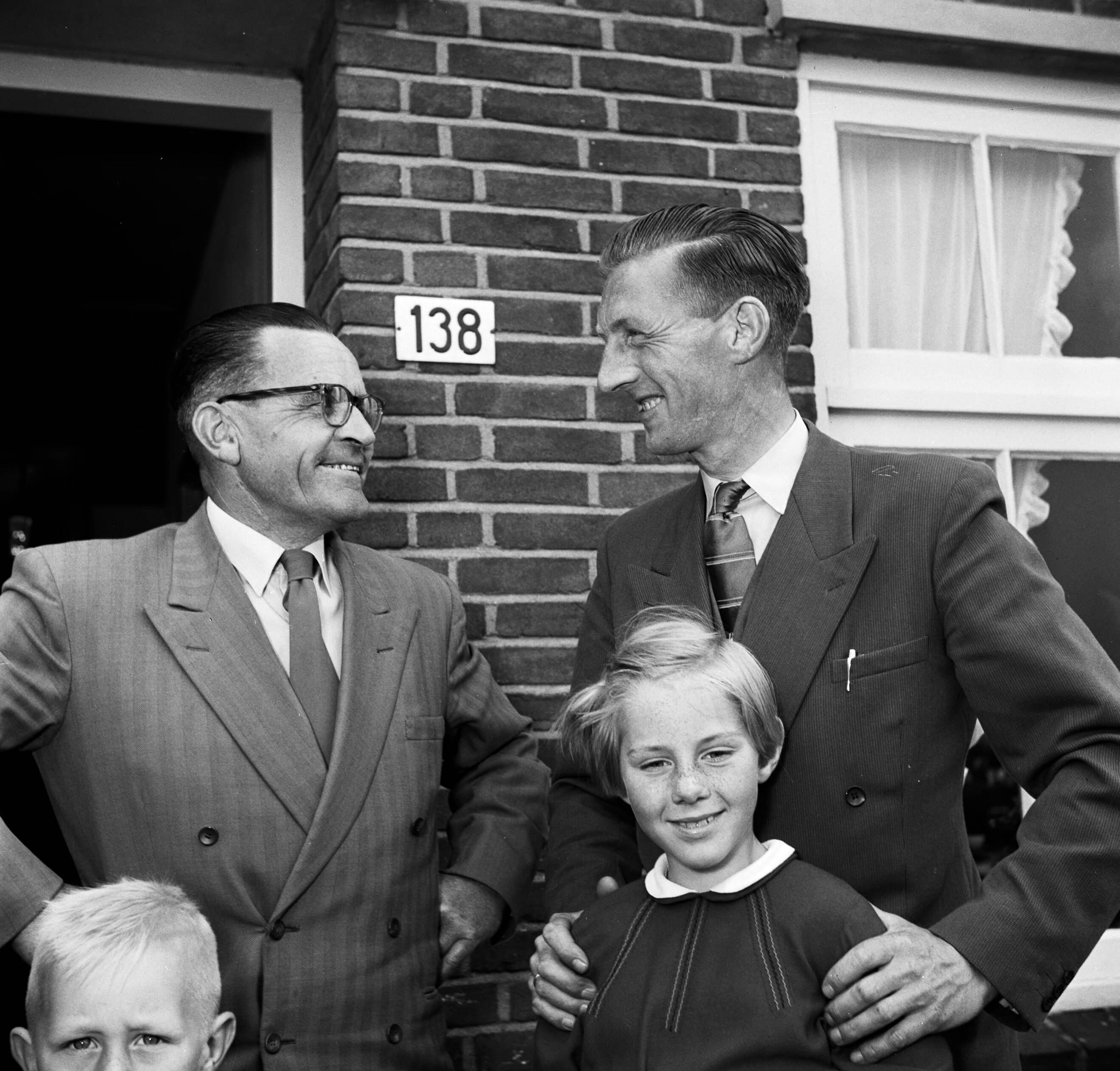 Fotocollectie Van de Poll — Gerard de Jong en Ynse Postma bij de voordeur van De Jongs woning. Voor De Jong zijn dochtertje Marietje. Links is nog net het hoofd van zijn zoontje Gerrie te zien — Foto: Poll, Willem van de. Licentie: Set B: Rechtenvrij / Publiek Domein. Bron: Nationaal Archief. http://hdl.handle.net/10648/aecce2e4-d0b4-102d-bcf8-003048976d84