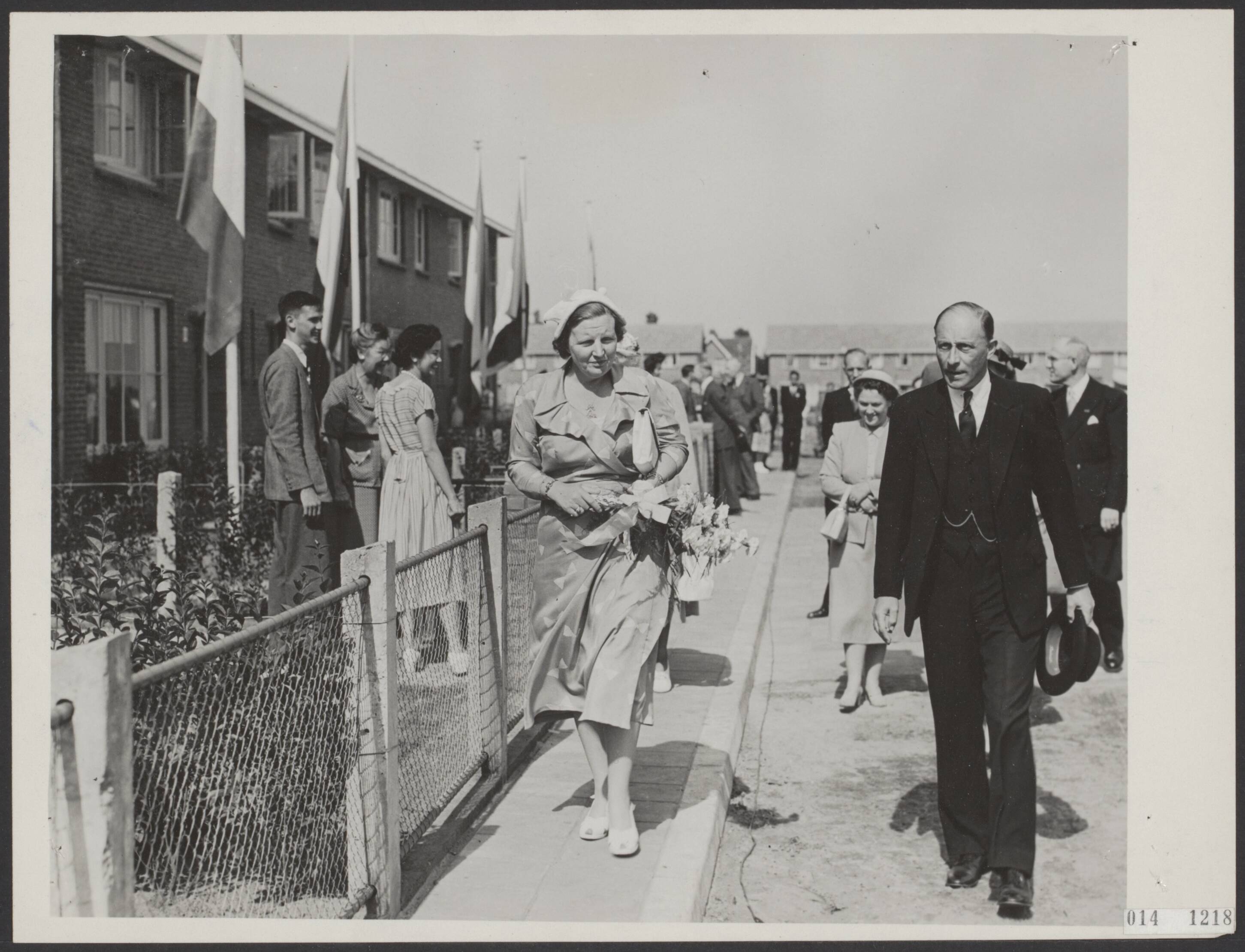Fotocollectie Elsevier Binnenland — Koningin Juliana stelt in Baarn een aantal woningen van de stichting "Pelita" in gebruik. Ze zijn bestemd voor gerepatrieerde oorlogsweduwen uit Indonesië. Begeleid door burgemeester mr. F.J. van Beeck Calkoen bezichtigt de koningin de versierde woningen — Foto: Fotograaf Onbekend / Anefo. Licentie: Set B: Rechtenvrij / Publiek Domein. Bron: Nationaal Archief. http://hdl.handle.net/10648/adb31c84-d0b4-102d-bcf8-003048976d84