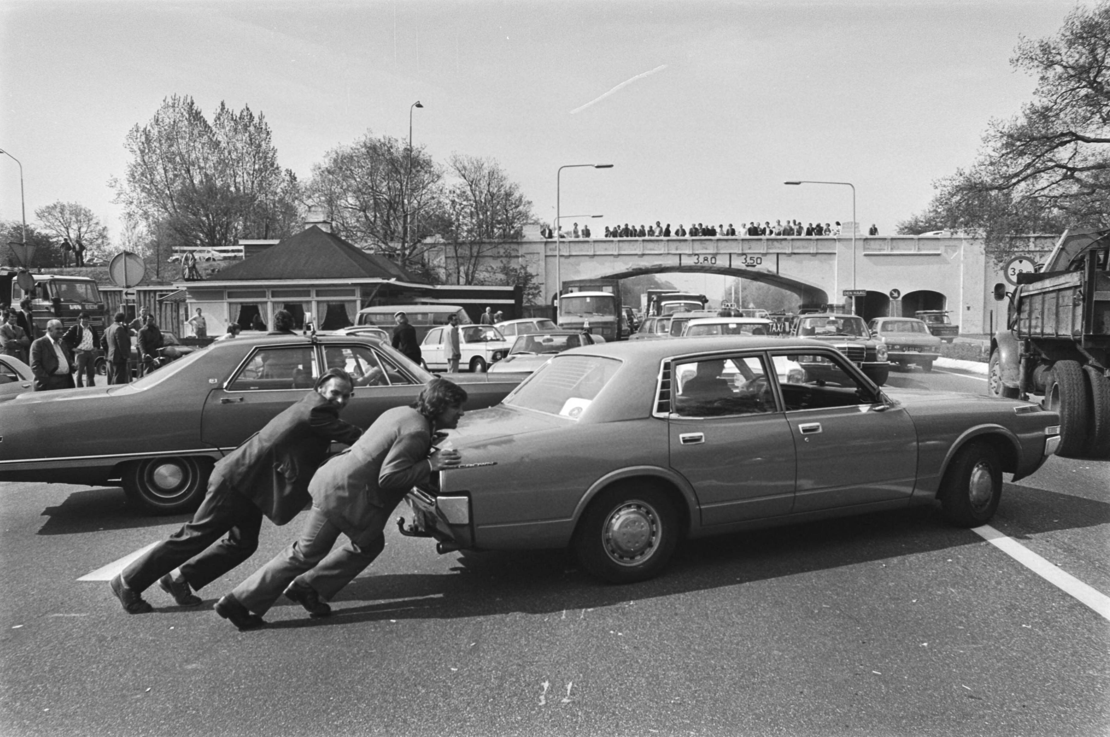 Fotocollectie Anefo — Taxiblokkades in Den Haag ; ongeduldige chauffeurs probeerden een taxi weg te duwen — Foto: Verhoeff, Bert / Anefo. Licentie: Set B: Rechtenvrij / Publiek Domein. Bron: Nationaal Archief. http://hdl.handle.net/10648/ac82f35c-d0b4-102d-bcf8-003048976d84