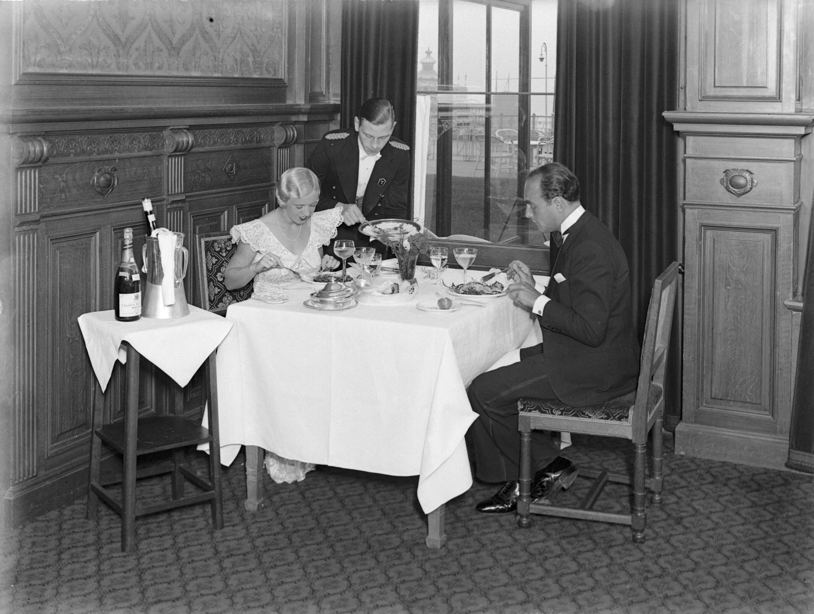Scheveningen. — Een man (Farrar?) en een vrouw (Yvonne?) bij het diner in het Palace Hotel in Scheveningen — Foto: Poll, Willem van de. Licentie: Set B: Rechtenvrij / Publiek Domein. Bron: Nationaal Archief. http://hdl.handle.net/10648/ae9abef4-d0b4-102d-bcf8-003048976d84