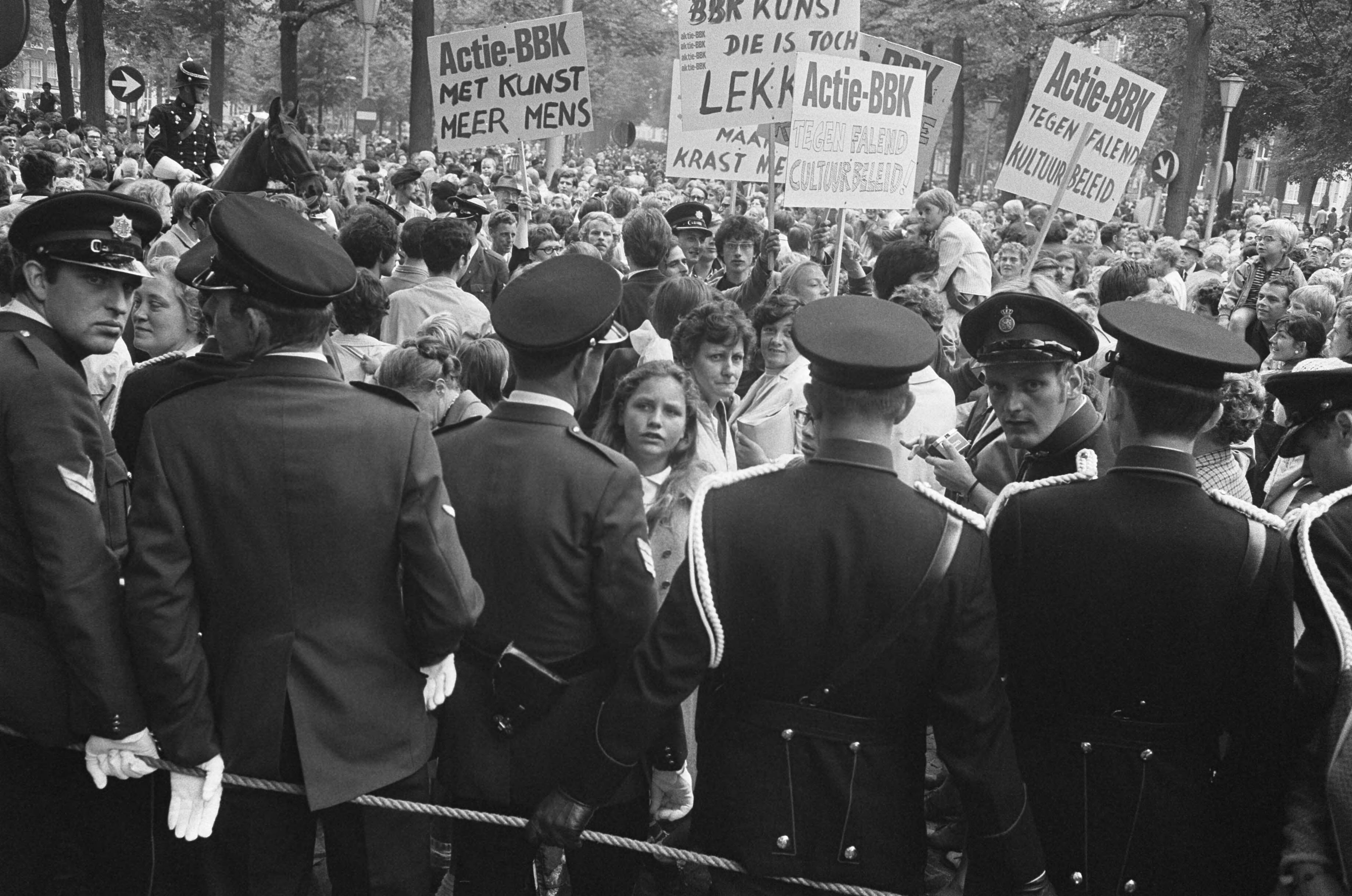 Fotocollectie Anefo — Kunstenaars van de BBK protesteren met borden tegen het cultuurbeleid op Lange Voorhout Den Haag tijdens rit Kon. Fam. naar Pal. Lange Voorhout : demonstrerende — Foto: Koch, Eric / Anefo. Licentie: Set B: Rechtenvrij / Publiek Domein. Bron: Nationaal Archief. http://hdl.handle.net/10648/ab7a0216-d0b4-102d-bcf8-003048976d84