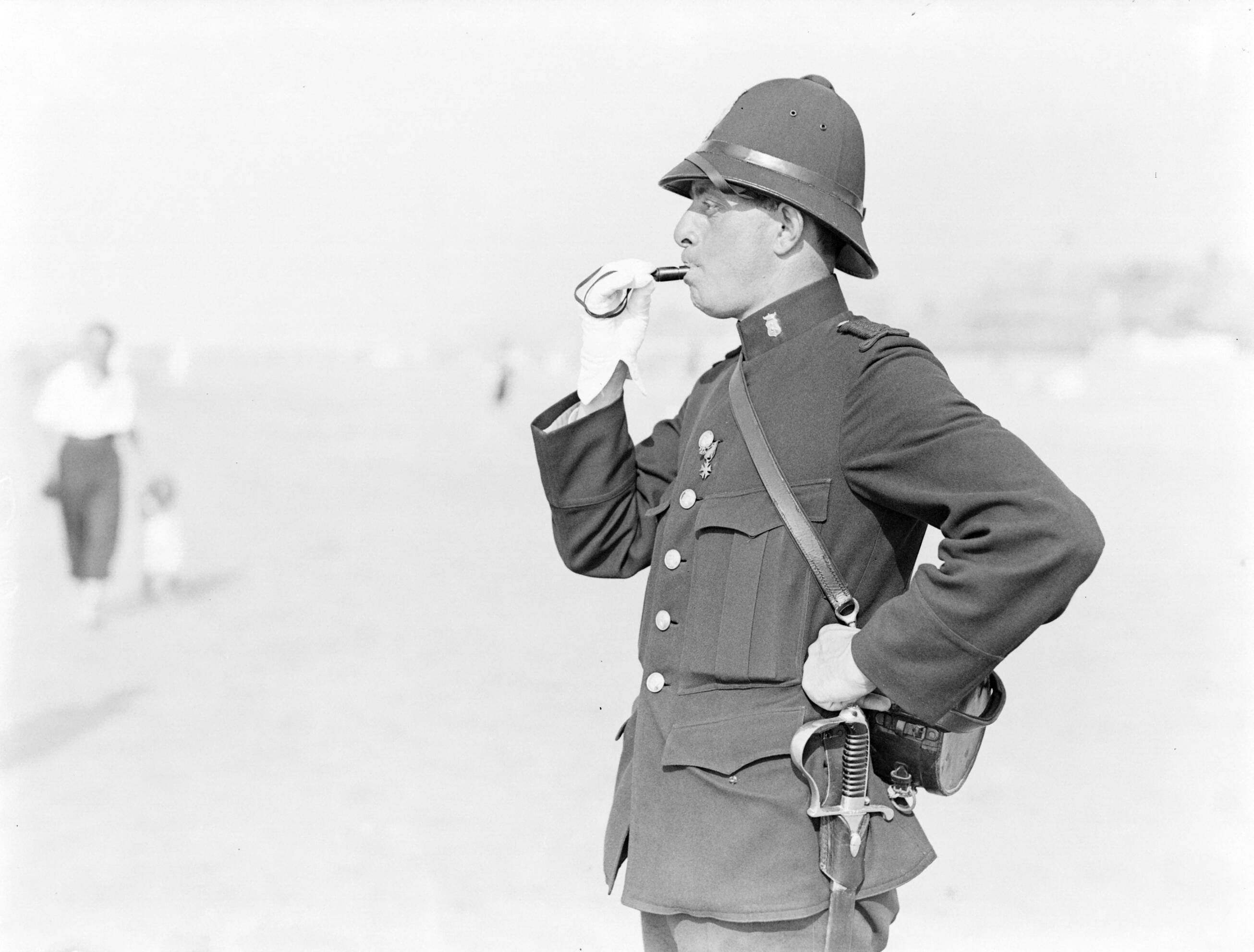 Scheveningen. — Politieagent Jaspers op het strand in Scheveningen — Foto: Poll, Willem van de. Licentie: Set B: Rechtenvrij / Publiek Domein. Bron: Nationaal Archief. http://hdl.handle.net/10648/aea9f13a-d0b4-102d-bcf8-003048976d84