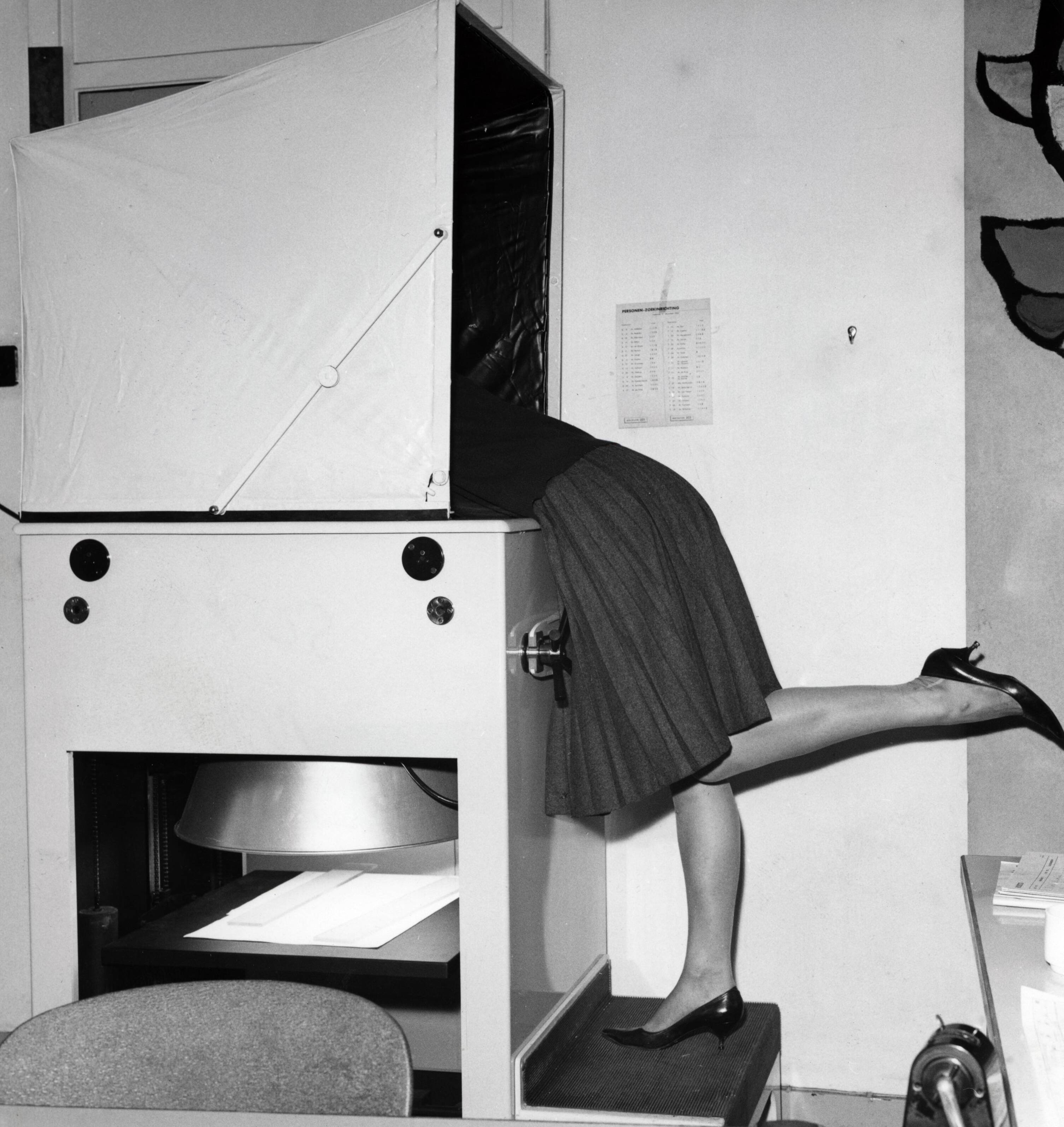 Collectie nader te bepalen — De andere helft van de enige lay out vrouw/vormgeefster wordt aan het oog onttrokken door de kap van de vergrotingskoker. Haarlem 1963. — Foto: Fotograaf Onbekend / Fotobureau onbekend / Spaarnestad Photo (05887). Licentie: Set B: Rechtenvrij / Publiek Domein. Bron: Nationaal Archief. http://hdl.handle.net/10648/35429da6-37fd-a382-e063-6df0900a6686