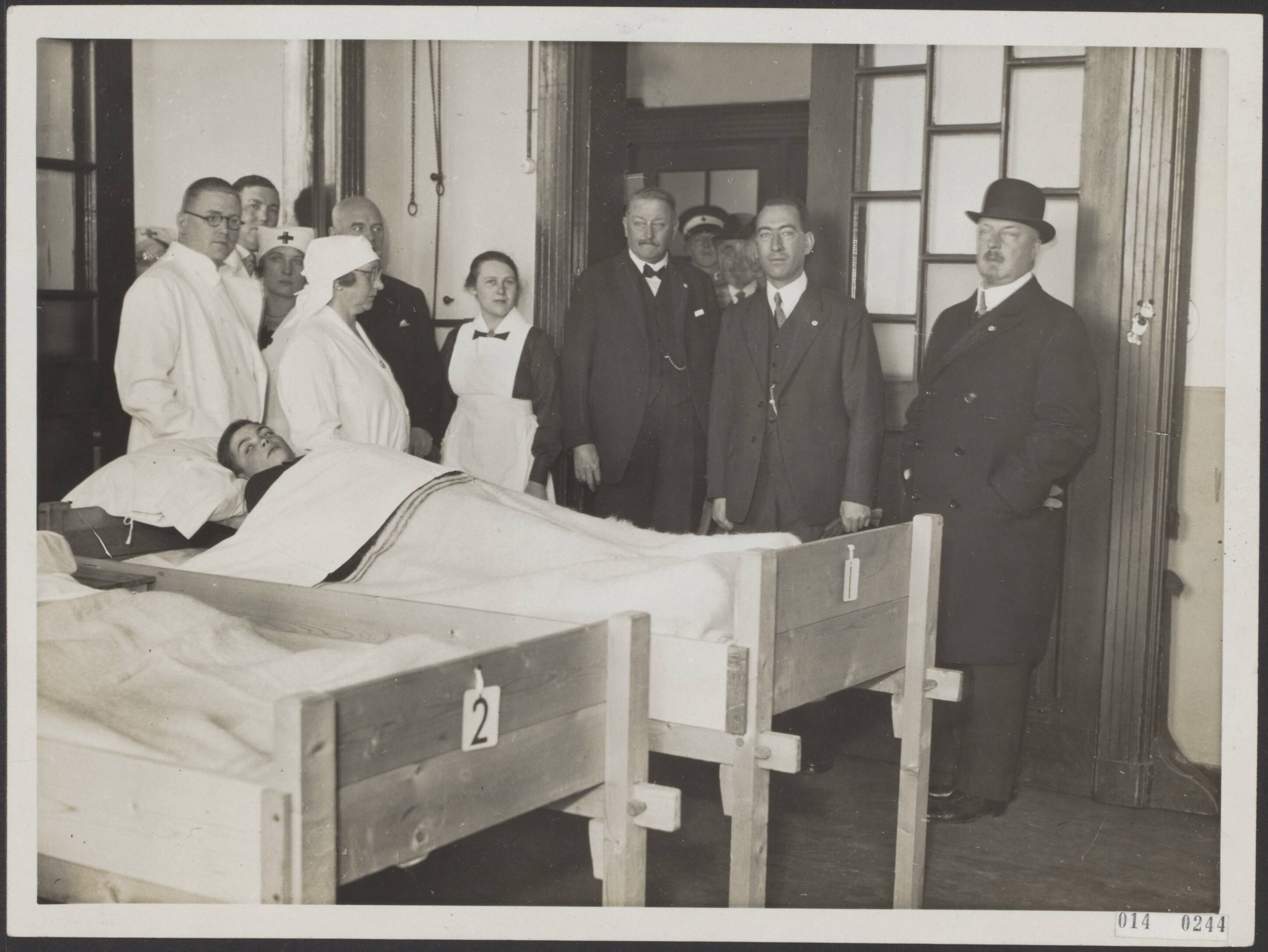 Fotocollectie Elsevier Binnenland — Demonstraties van het Nederlandse Rode Kruis. De oefening bestond uit het inrichten van een school tot noodhospitaal in één dag. Prins Hendrik in het geimproviseerde schoolhospitaal. Naast hem de burgemeester van Veenendaal, mr. J.J.P.C. van Kuyck — Foto: N.V. Polygoon. Licentie: Set B: Rechtenvrij / Publiek Domein. Bron: Nationaal Archief. http://hdl.handle.net/10648/adb008a0-d0b4-102d-bcf8-003048976d84