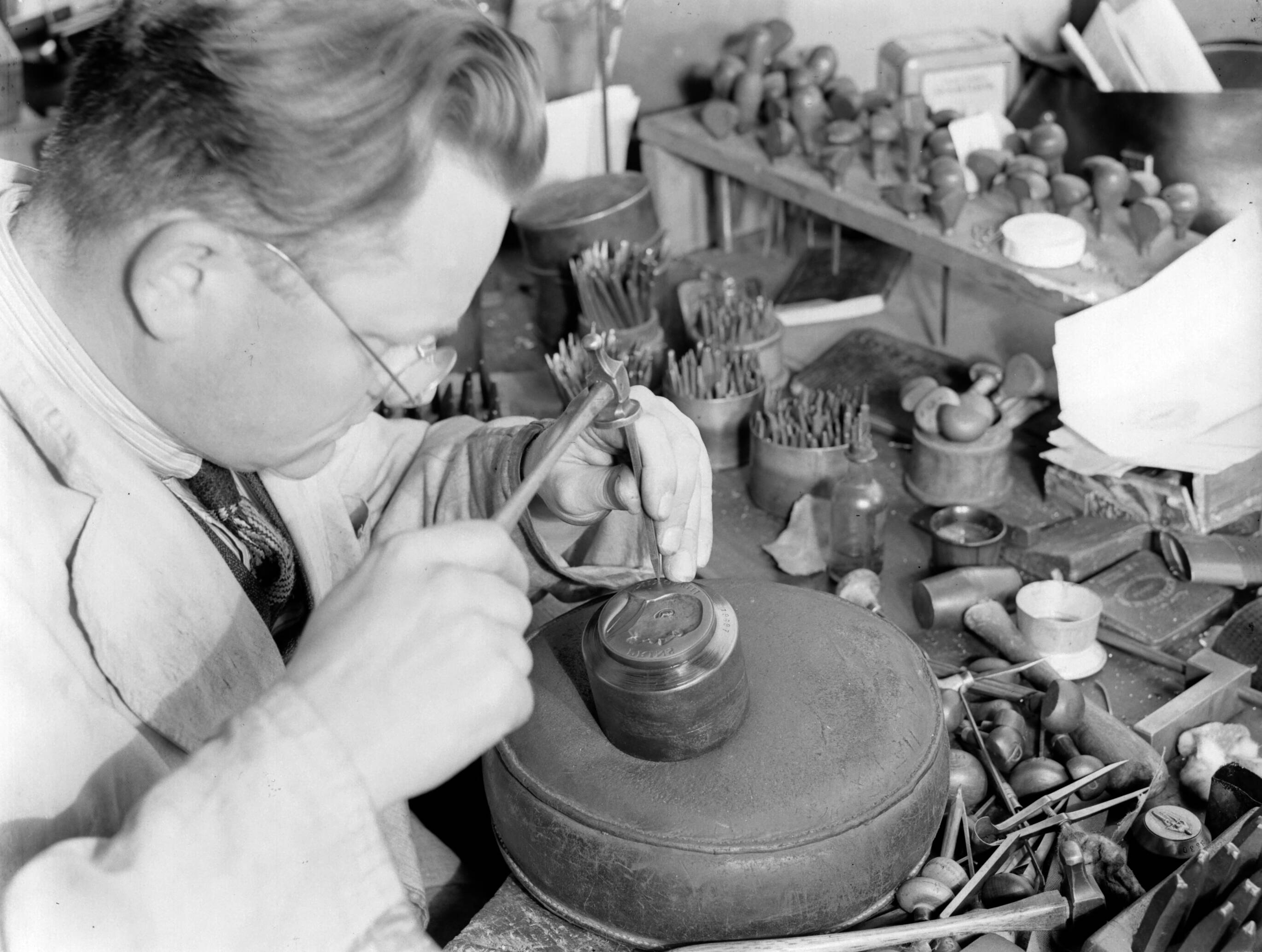 Productfoto's; zilverwerk — Arbeider bezig met gravure bij de fa. Gerritsen & Van Kempen in Zeist, hij gebruikt diverse naalden — Foto: Poll, Willem van de. Licentie: Set B: Rechtenvrij / Publiek Domein. Bron: Nationaal Archief. http://hdl.handle.net/10648/ae9e38d6-d0b4-102d-bcf8-003048976d84