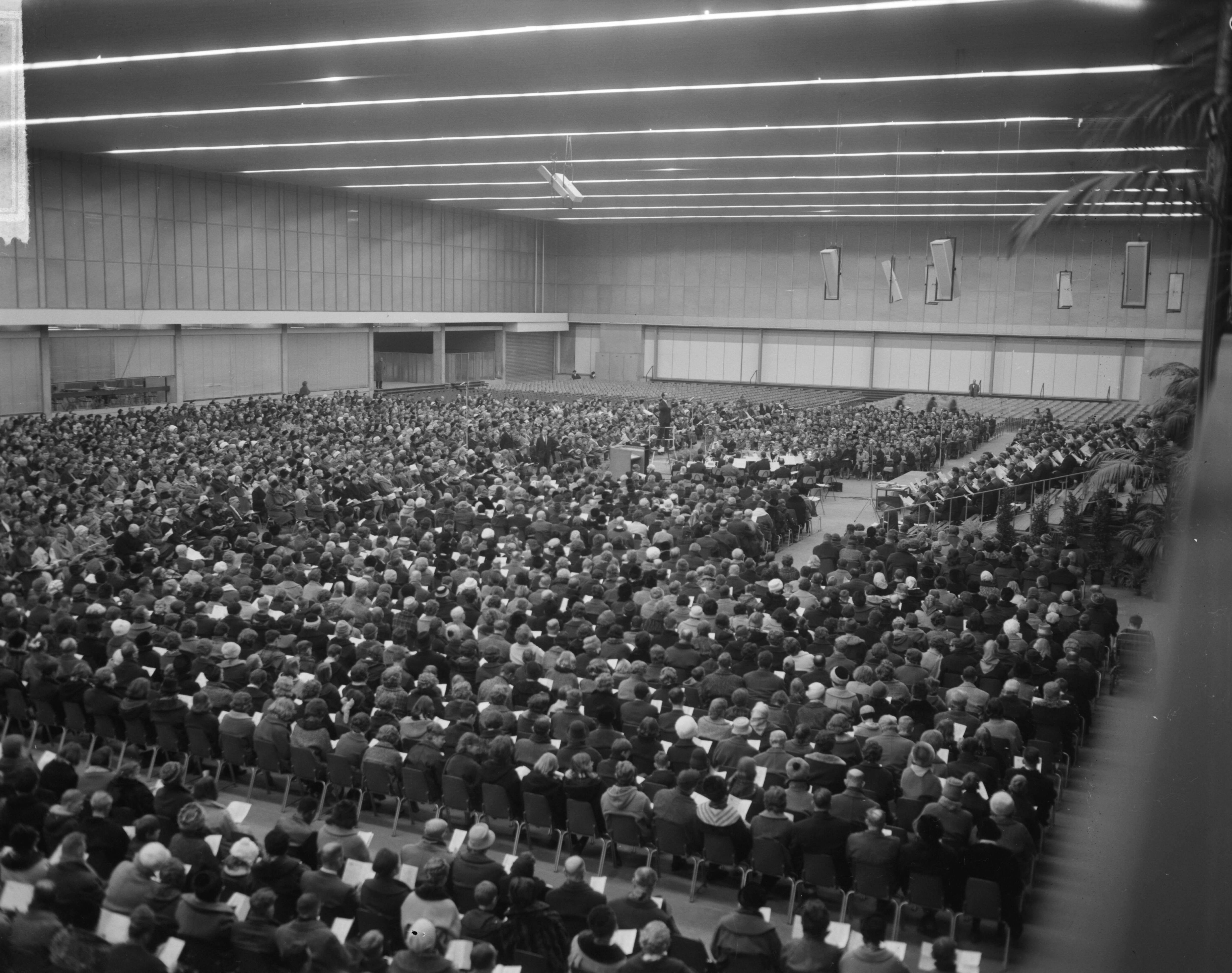 Fotocollectie Anefo — Samenzang in het nieuwe RAI-gebouw te Amsterdam door 5000 mensen — Foto: Bilsen, Joop van / Anefo. Licentie: Set B: Rechtenvrij / Publiek Domein. Bron: Nationaal Archief. http://hdl.handle.net/10648/aa8a1aa8-d0b4-102d-bcf8-003048976d84