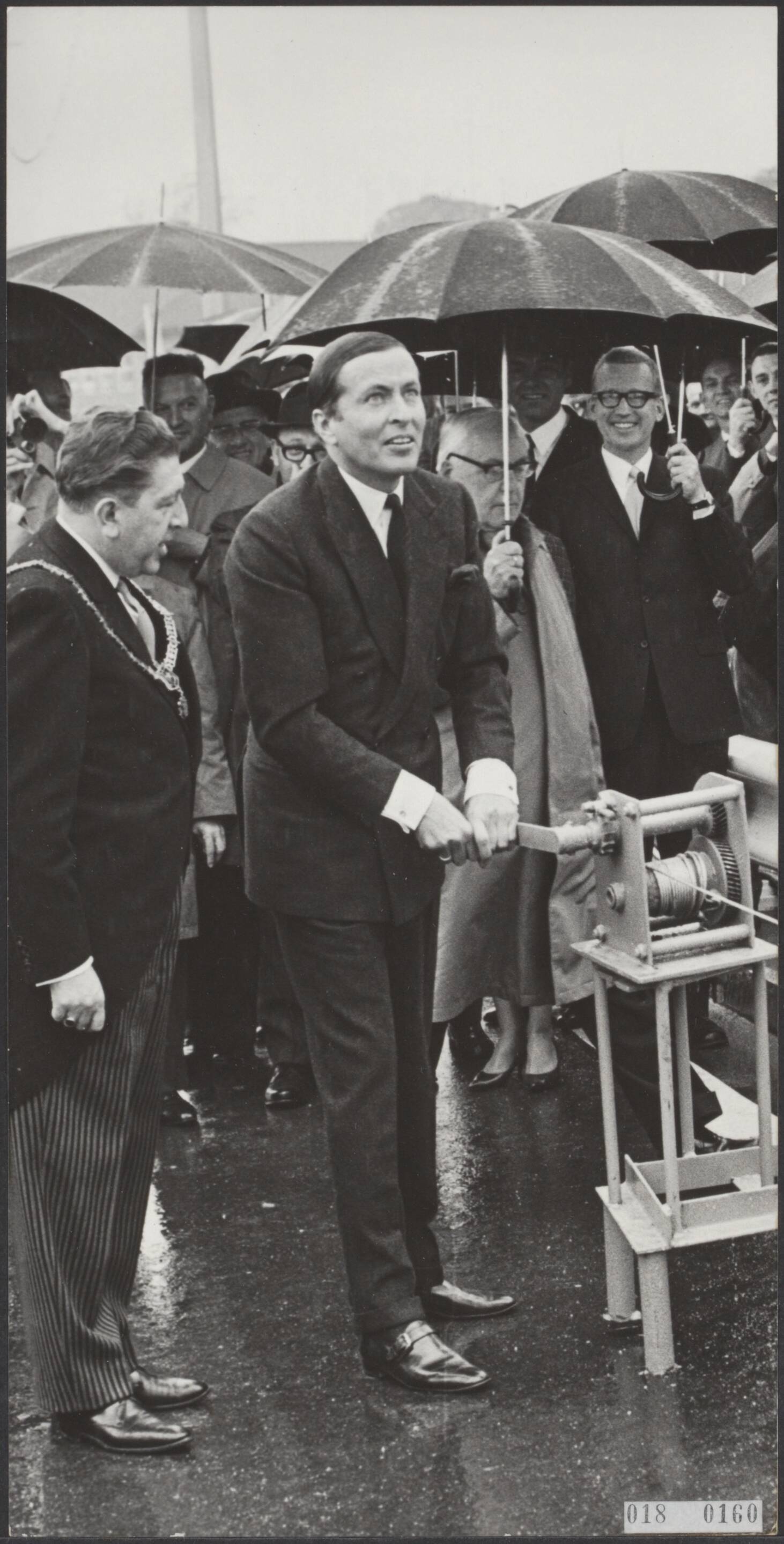 Fotocollectie Elsevier Binnenland — Prins Claus heeft de officiële opening verricht van de John F. Kennedybrug over de Maas te Maastricht. Prins Claus draait via een lier een bord omhoog waarop "John F. Kennedybrug" en daarmee het verkeer over de brug kan rijden . Rechts de burgemeester van Maastricht, A.M.I.H. Baeten, — Foto: Nijs, Jac. de / Anefo. Licentie: Set B: Rechtenvrij / Publiek Domein. Bron: Nationaal Archief. http://hdl.handle.net/10648/adc166c2-d0b4-102d-bcf8-003048976d84