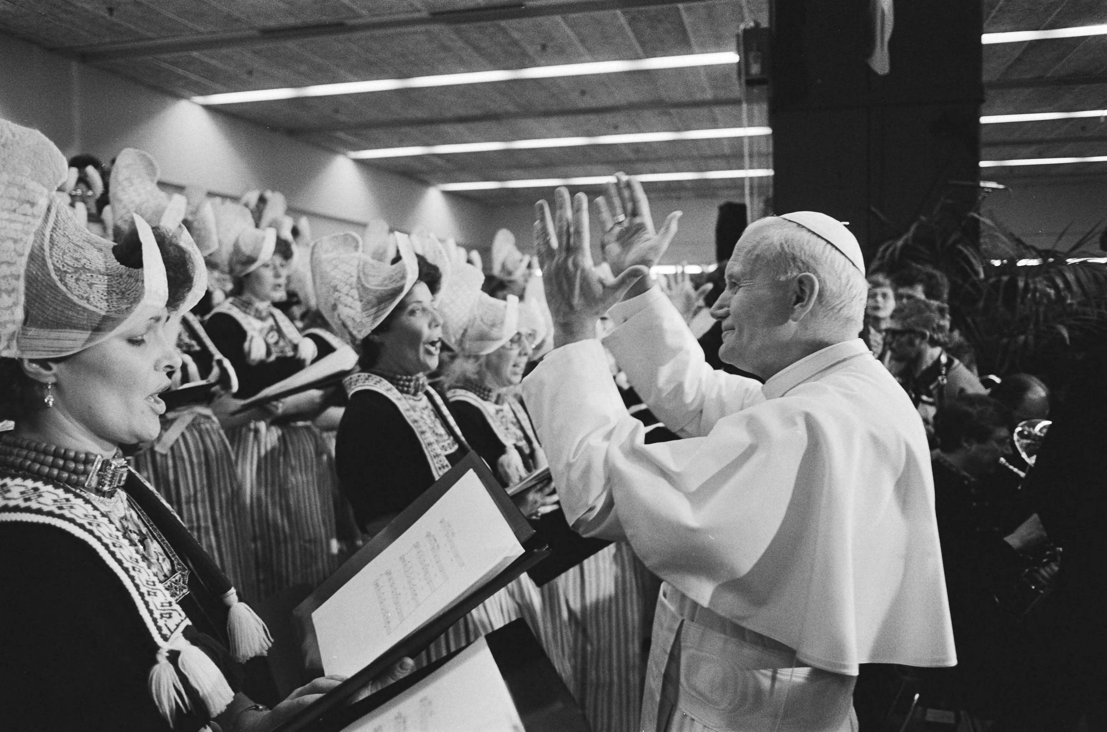 Fotocollectie Anefo — Paus luistert aandachtig naar maatschappelijke organisati in de Jaarbeurs in Utrecht; in Utrecht luisterde de Paus dit Volendams koor — Foto: Croes, Rob C. / Anefo. Licentie: Set B: Rechtenvrij / Publiek Domein. Bron: Nationaal Archief. http://hdl.handle.net/10648/ad4698ac-d0b4-102d-bcf8-003048976d84