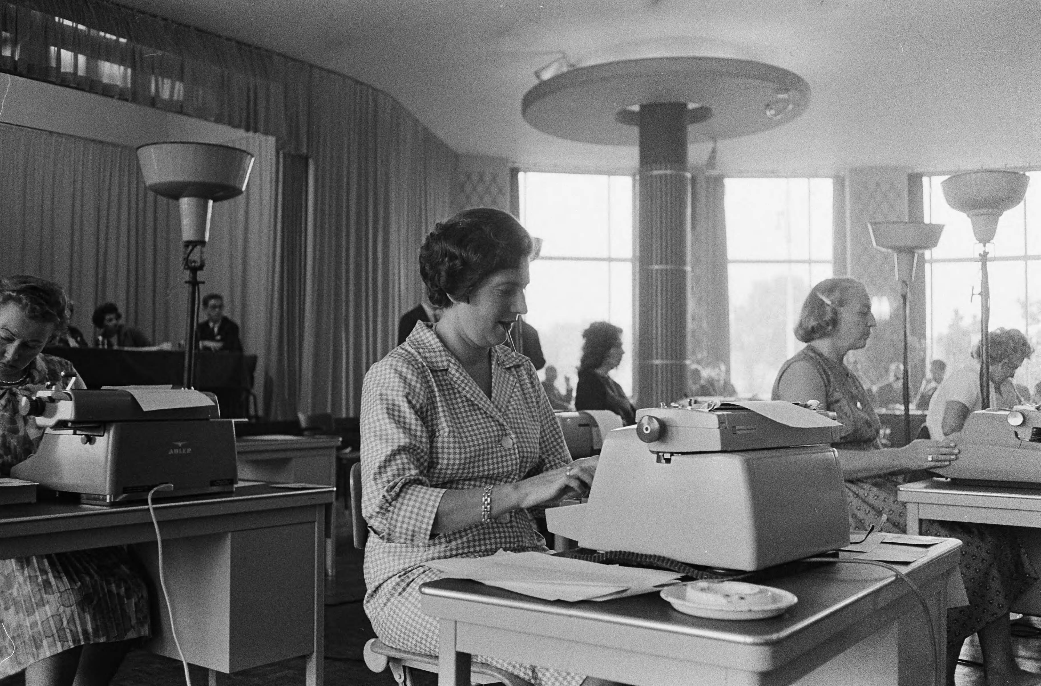 Fotocollectie Anefo — Nationale Kampioenschappen machineschrijven in de Rotonde van de Houtrusthallen te Den Haag. De kampioene van vorig jaar mevrouw J. C. Machwirth-Bijloo aan het typen — Foto: Walta, Winfried / Anefo. Licentie: Set B: Rechtenvrij / Publiek Domein. Bron: Nationaal Archief. http://hdl.handle.net/10648/aa464148-d0b4-102d-bcf8-003048976d84