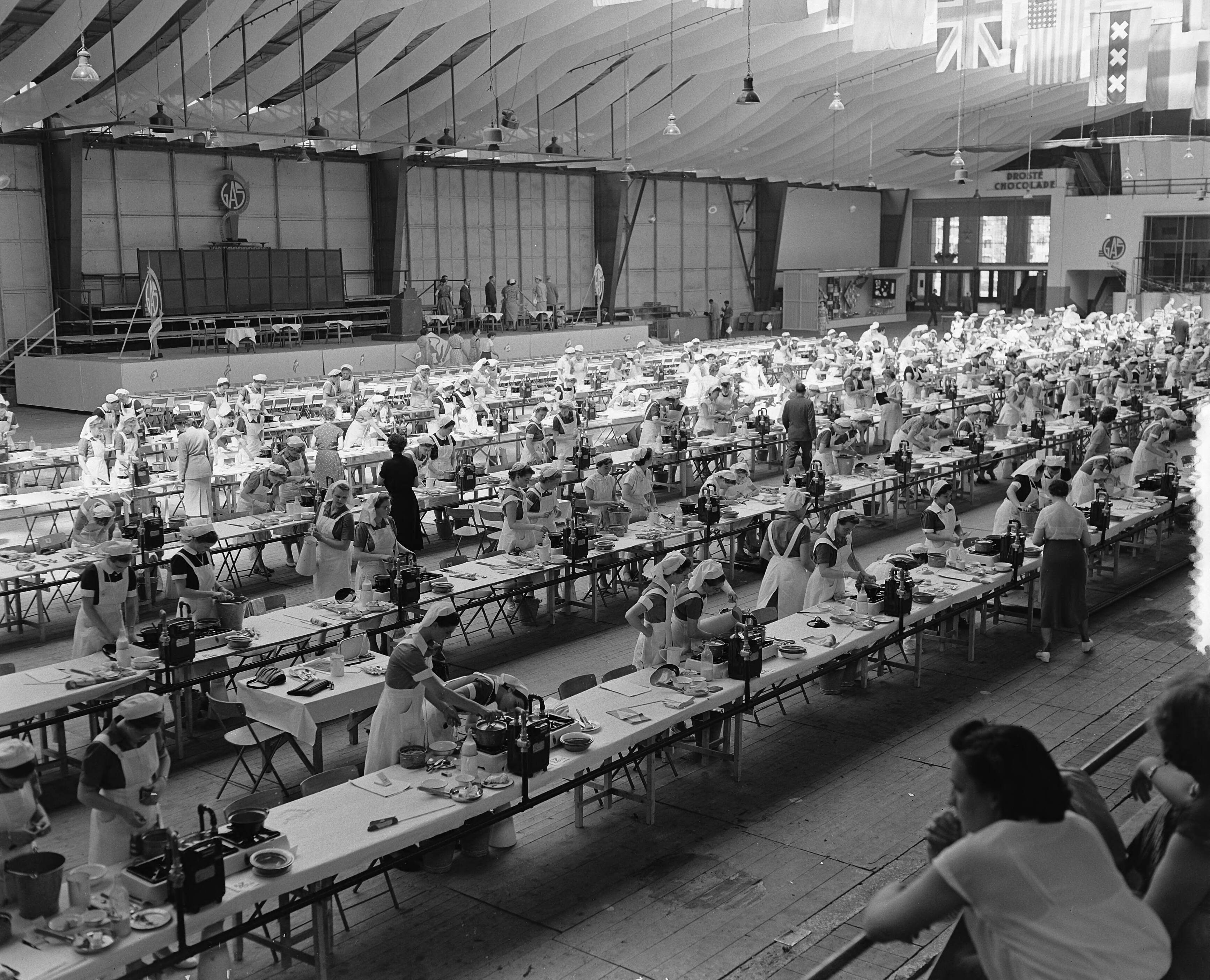 Fotocollectie Anefo — B. K. Kookwedstrijd in de Houtrusthallen te Den Haag — Foto: Rossem, Wim van / Anefo. Licentie: Set B: Rechtenvrij / Publiek Domein. Bron: Nationaal Archief. http://hdl.handle.net/10648/a921d1ec-d0b4-102d-bcf8-003048976d84