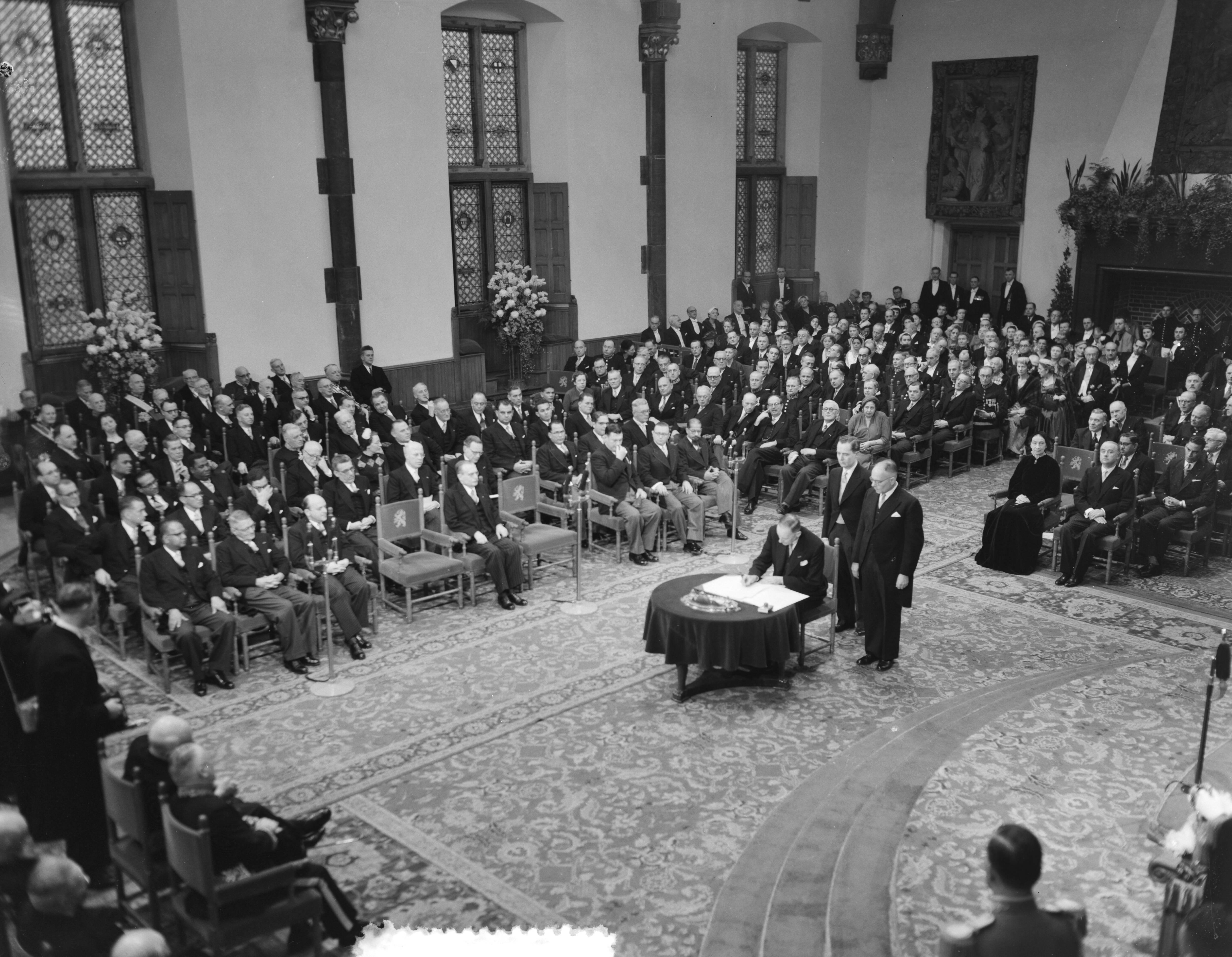 Koningin Juliana ondertekent in een plechtige bijeenkomst in de Ridderzaal in Den Haag de Acte van Bevestiging van het Statuut voor het Koninkrijk — Ondertekening van de Acte van Bevestiging van het Statuut van het Koninkrijk in de Ridderzaal te Den Haag. Verschillende ministers ondertekenen de akte — Foto: Noske, J.D. / Anefo. Licentie: Set B: Rechtenvrij / Publiek Domein. Bron: Nationaal Archief. http://hdl.handle.net/10648/a92e1df8-d0b4-102d-bcf8-003048976d84