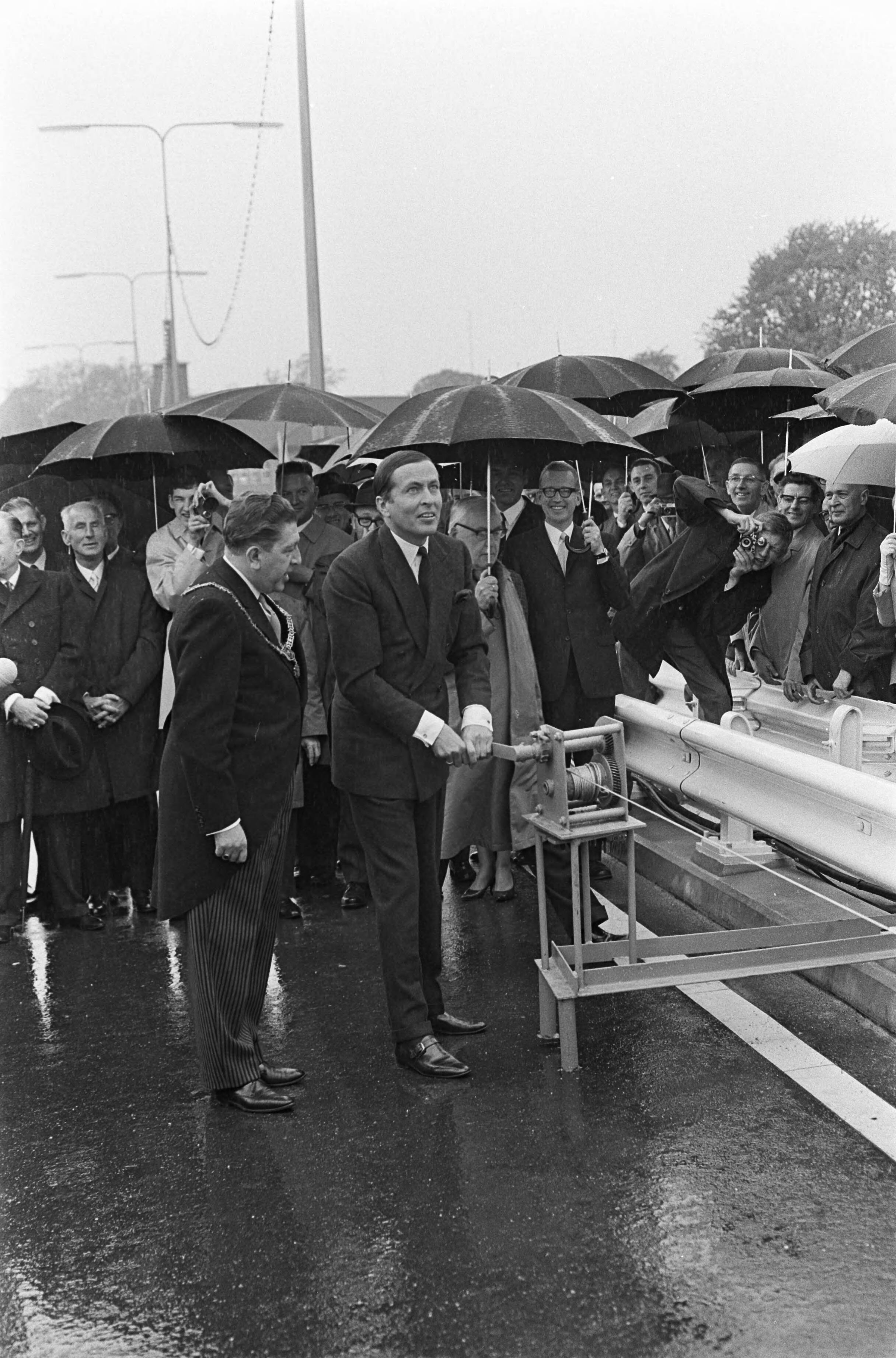 Fotocollectie Anefo — Prins Claus opende John F. Kennedy brug te Maastricht. De prins draait via een lierbord omhoog waar naam op staat. Links naast de prins burgemeester mr. A.M.I. (Fons) Baeten — Foto: Nijs, Jac. de / Anefo. Licentie: Set B: Rechtenvrij / Publiek Domein. Bron: Nationaal Archief. http://hdl.handle.net/10648/ab3fbdd6-d0b4-102d-bcf8-003048976d84
