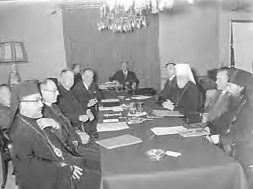 Fotocollectie Anefo — Gesprek Wereldraad van Kerken en de Russisch Orthodoxe Kerk te Utrecht, De beide delegaties aan de conferentietafel. Links van voor naar achter de metropoliet James van Melita, de tolk dr. John Lawrence, dr. Franklin Clark Fry, voorzitter van het Centraal Comité van de Wereldraad van Kerken en dr. W.A. Visser 't Hooft, secretaris-generaal van de Wereldraad. Rechts van achter naar voren: dr. Buevsky van de Moskouse delegatie, metropliet Nikolaj van Kroetitsky en Colomna, de tolk Alexeief en de aartsbisschop van Smolensk — Foto: Behrens, Herbert F. / Anefo. Licentie: Set B: Rechtenvrij / Publiek Domein. Bron: Nationaal Archief. http://hdl.handle.net/10648/a9822218-d0b4-102d-bcf8-003048976d84