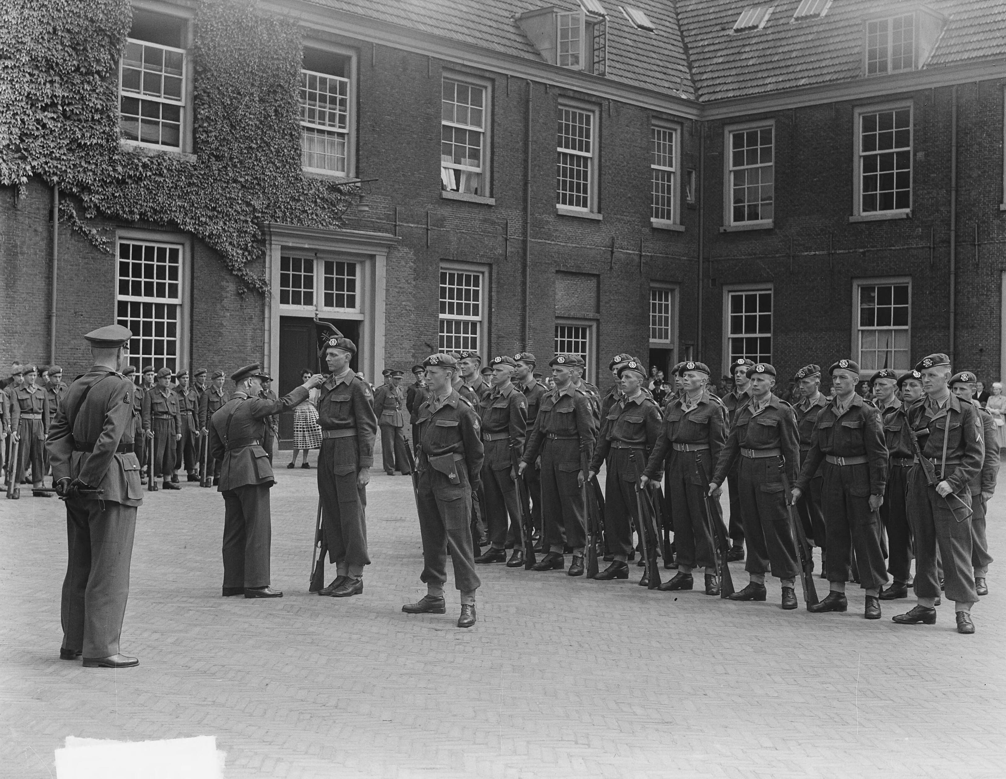 Inspectie en defilé te Haarlem t.g.v. afscheid Luchtdoelafdeling — Inspectie en defilé te Haarlem t.g.v. afscheid van het regiment lichte luchtdoelartillerie "Betuwe". Soldaat H.J. Beernink ontvangt als beste soldaat van de vijfde klasse der kanonnierbatterij het regimentsvaantje van regimentscommandant luitenant-kolonel Van Driem — Foto: Vogel, Carel L. de / Anefo. Licentie: Set B: Rechtenvrij / Publiek Domein. Bron: Nationaal Archief. http://hdl.handle.net/10648/a8eb8ca4-d0b4-102d-bcf8-003048976d84