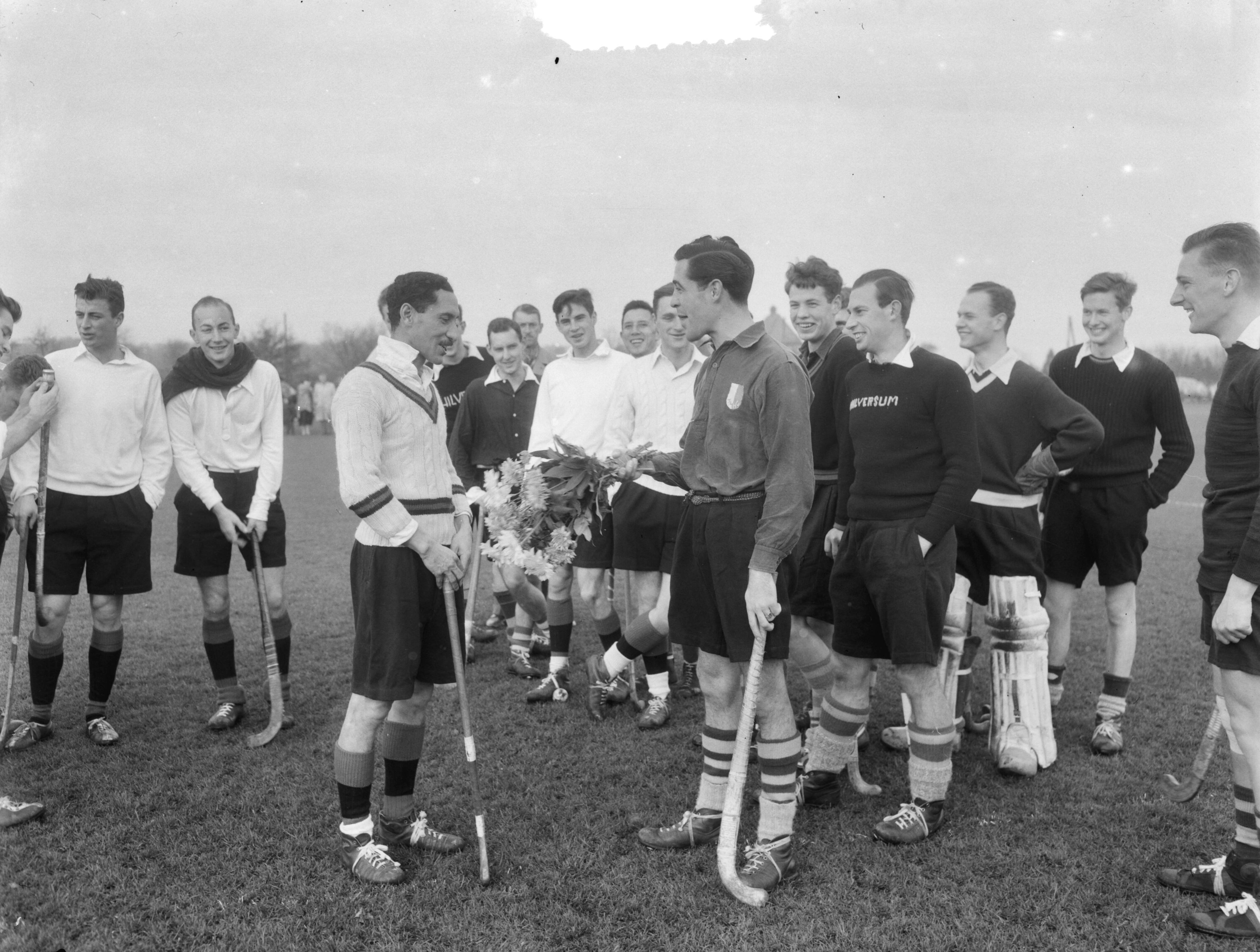 Fotocollectie Anefo — Huldiging hockeyer Dick Esser. Laatste wedstrijd voor Amsterdam in een wedstrijd te Hilversum. Aanbieding bloemen door captain van Hilversum — Foto: Duinen, G.W. van / Anefo. Licentie: Set B: Rechtenvrij / Publiek Domein. Bron: Nationaal Archief. http://hdl.handle.net/10648/a9185f68-d0b4-102d-bcf8-003048976d84