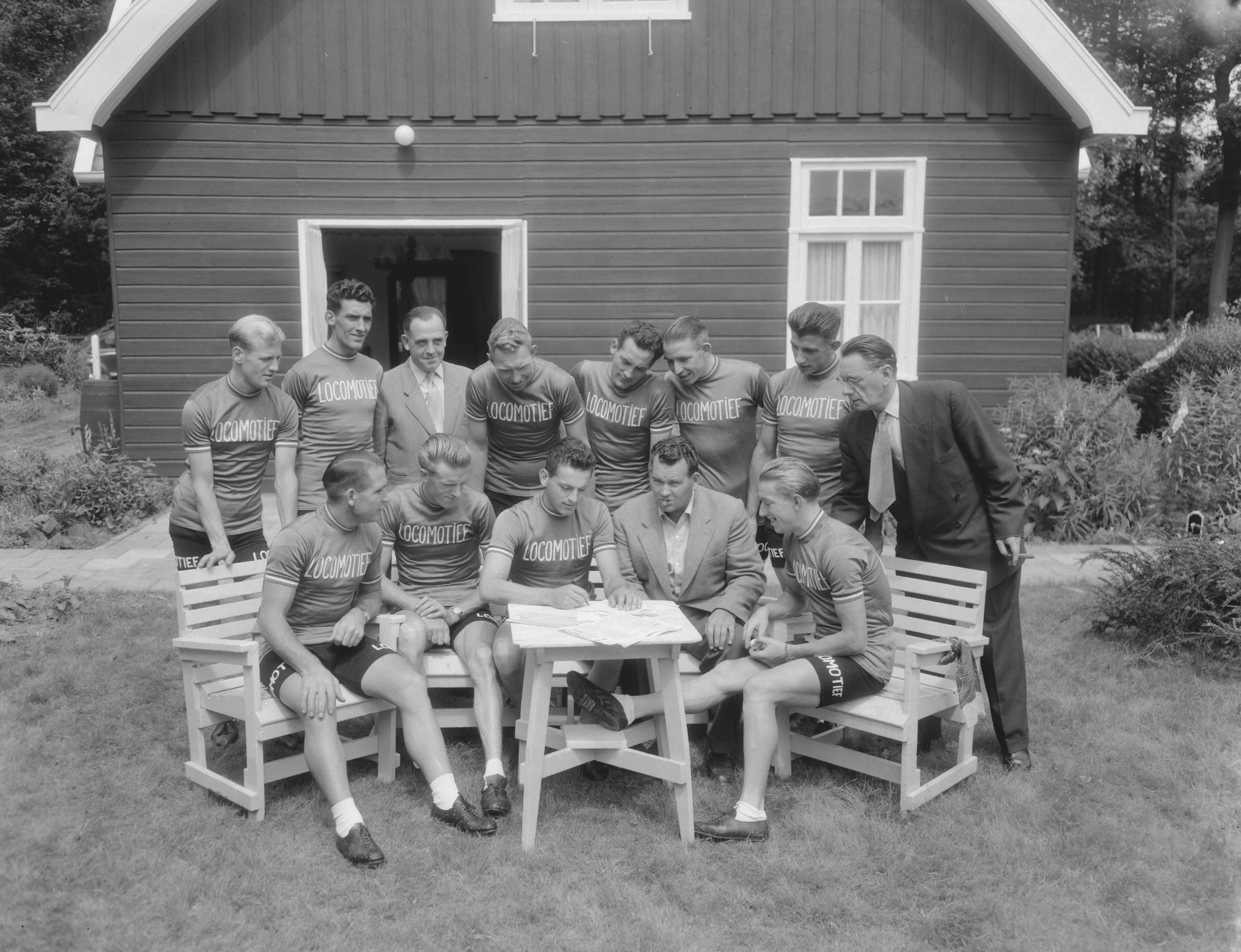 Ondertekening van contracten van Tour de France ploeg ten huize van Cees Pellenaars te Breda — Ondertekening van contracten van Tour de France ploeg ten huize van Cees Pellenaars te Breda, groep [staand vlnr. Adri Suijkerbuijk, Gerrit Voorting, ?, Henk Faanhof, Hein van Breenen, Nico van Est, Thijs Roks, ?. Zittend vlnr. Wim van Est, Jan Nolten, Jules Maenen, Cees Pellenaars en Wout Wagtmans — Foto: Duinen, G.W. van / Anefo. Licentie: Set B: Rechtenvrij / Publiek Domein. Bron: Nationaal Archief. http://hdl.handle.net/10648/a924ad18-d0b4-102d-bcf8-003048976d84