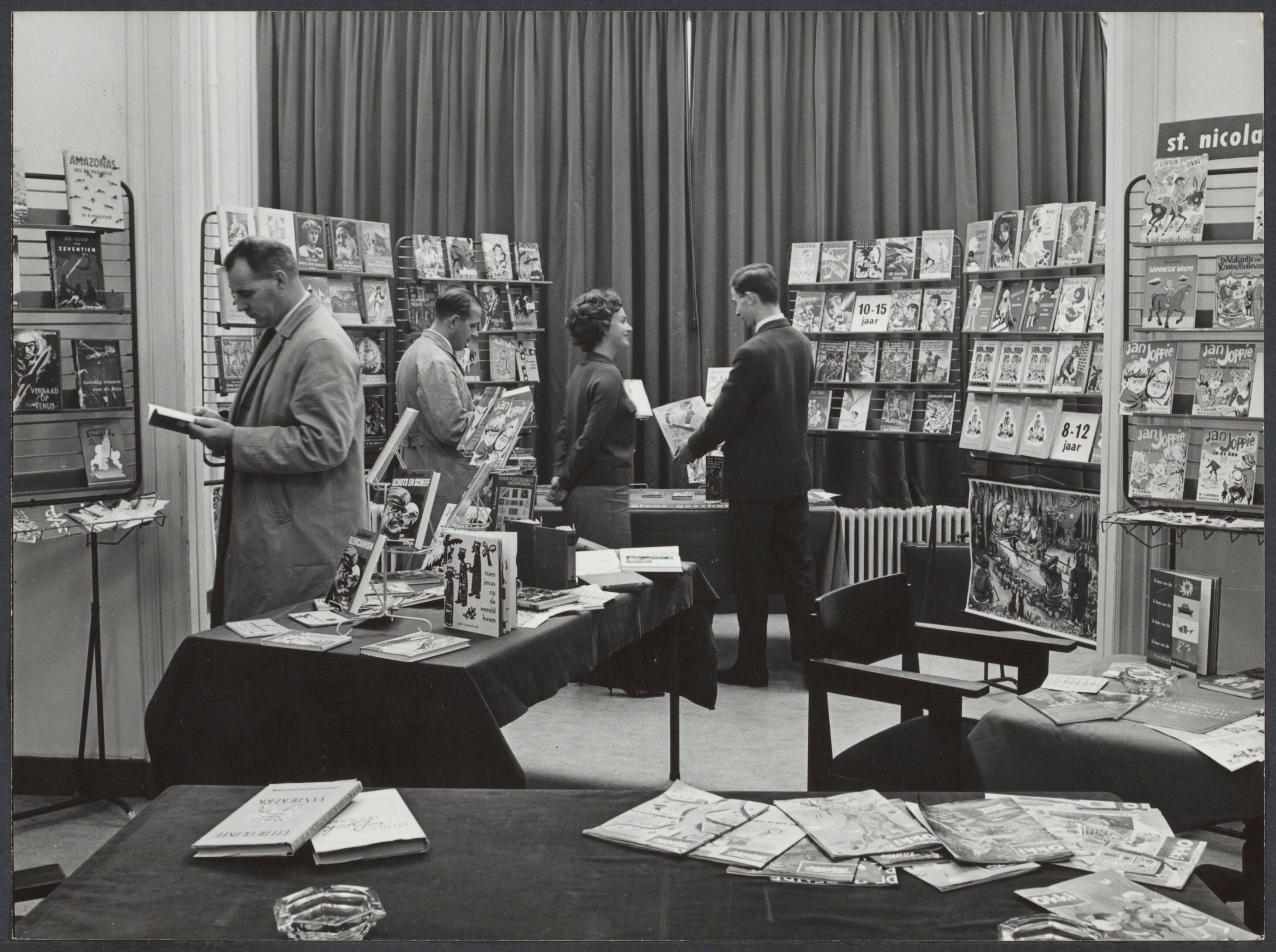 Spaarnestad, winstdeling, personeelsbibliotheek - Nederland — Serie: Personeelsbibliotheek "Zwartepiet" in gesprek met de heer Alkemade, die tijdens de tentoonstelling alle inlichtingen zal kunnen geven. Zo ongeveer zal de vergaderzaal aan de Nieuwe Gracht er uitzien op 18 november — Foto: Boer, F. de / Spaarnestad Photo (05887). Licentie: Set B: Rechtenvrij / Publiek Domein. Bron: Nationaal Archief. http://hdl.handle.net/10648/5903f154-be7e-a56d-85f3-212267f0e686