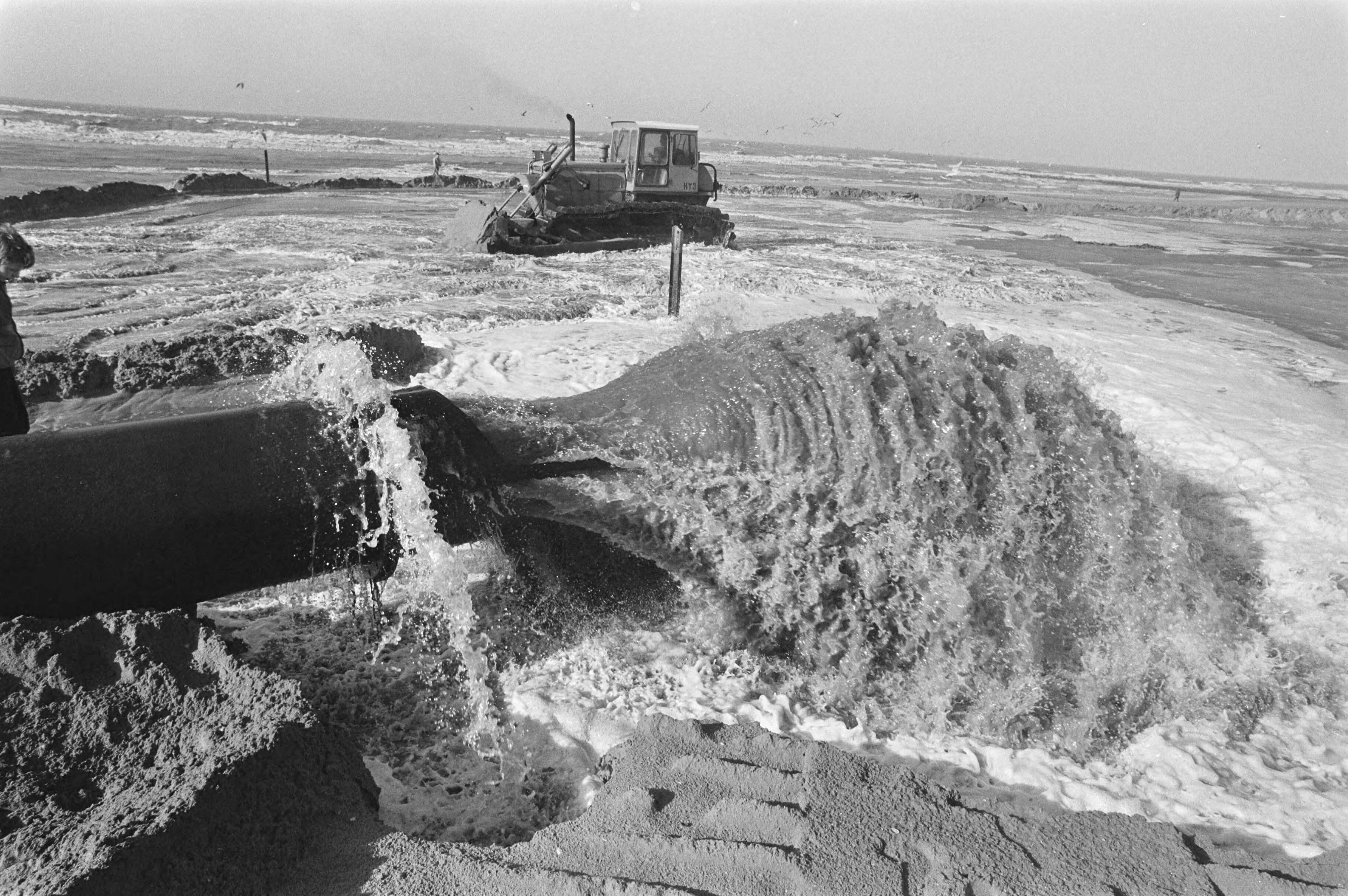 Fotocollectie Anefo — Scheveningse strand wordt opgespoten met zand wat 8 km uit de kust wordt opgezogen — Foto: Bogaerts, Rob / Anefo. Licentie: Set B: Rechtenvrij / Publiek Domein. Bron: Nationaal Archief. http://hdl.handle.net/10648/ad4414f6-d0b4-102d-bcf8-003048976d84