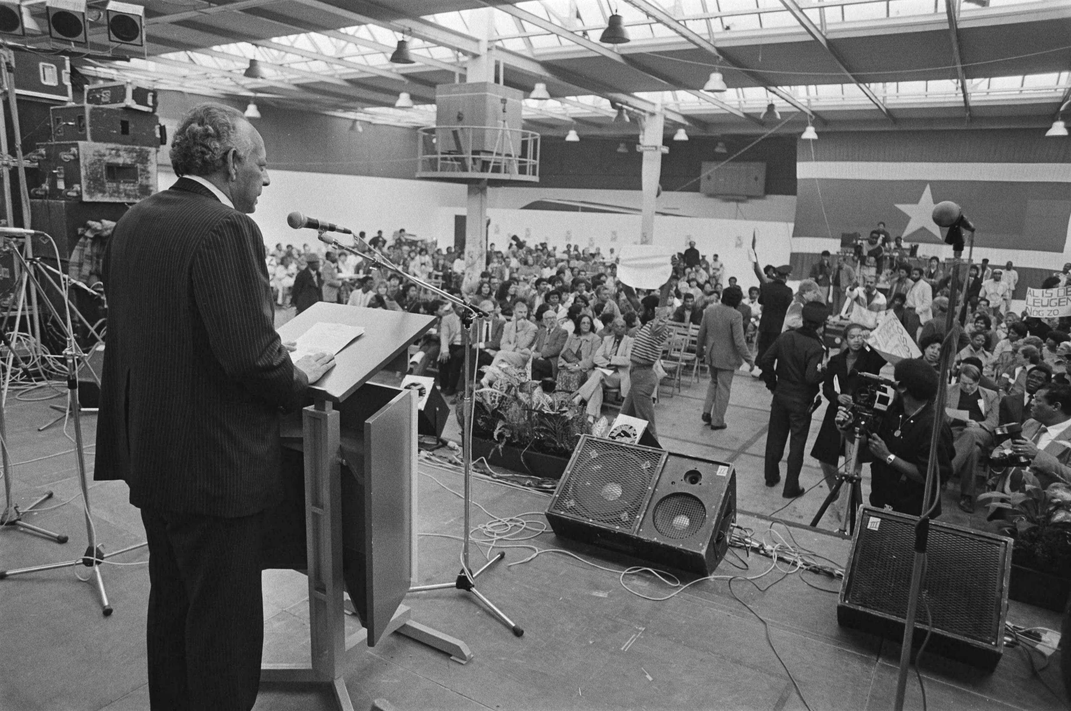 Fotocollectie Anefo — Herdenking onafhankelijkheidsdag Suriname in de Jaarbeurs Utrecht ambassadeur Heidweiller tijdens zijn rede — Foto: Bogaerts, Rob / Anefo. Licentie: Set B: Rechtenvrij / Publiek Domein. Bron: Nationaal Archief. http://hdl.handle.net/10648/ad403ac0-d0b4-102d-bcf8-003048976d84