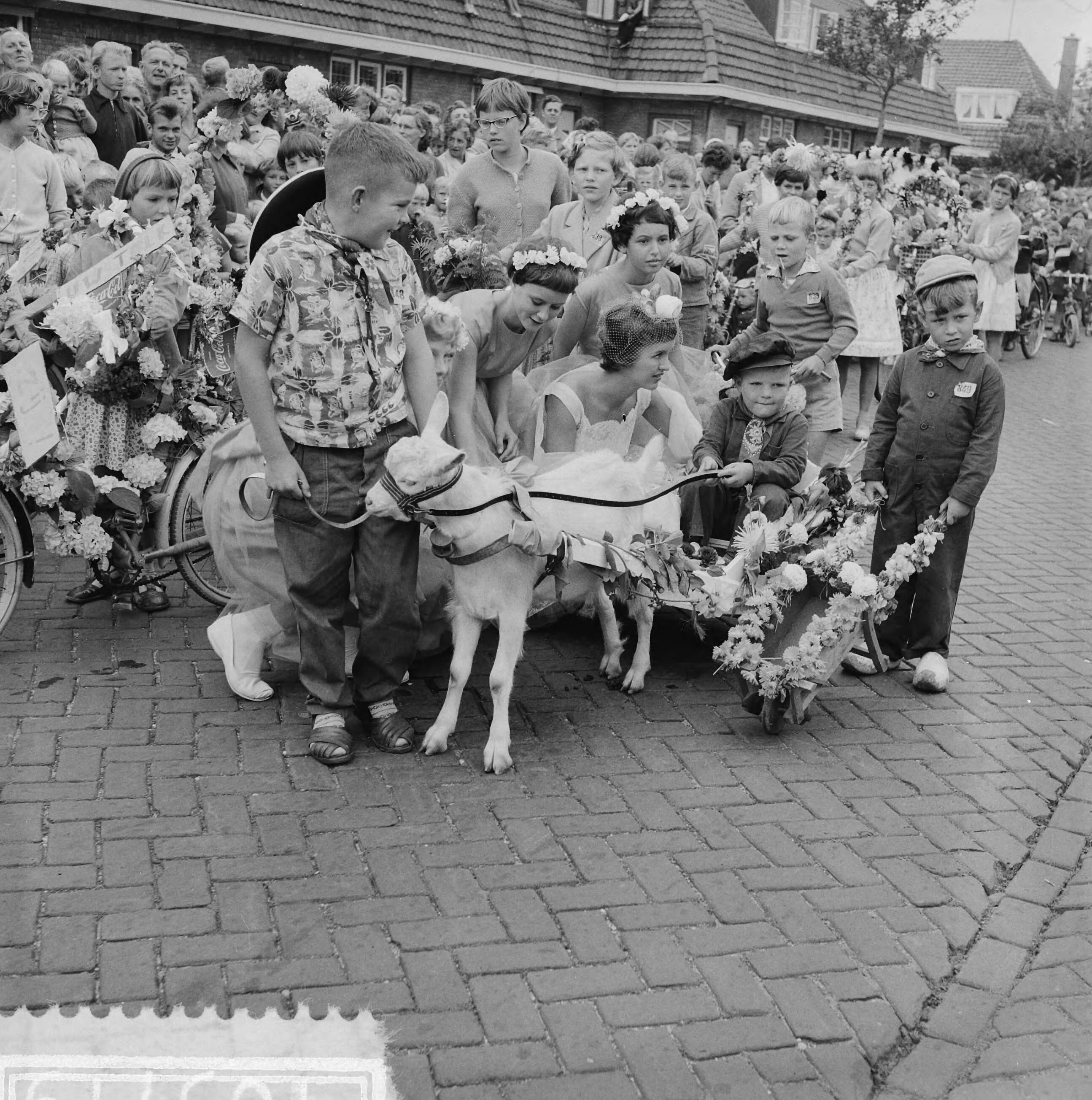 Fotocollectie Anefo — Kinderbloemencorso in Loosduinen, bloemenkoningin en prinsessen bekijken wagentje — Foto: Behrens, Herbert F. / Anefo. Licentie: Set B: Rechtenvrij / Publiek Domein. Bron: Nationaal Archief. http://hdl.handle.net/10648/a99a5f22-d0b4-102d-bcf8-003048976d84