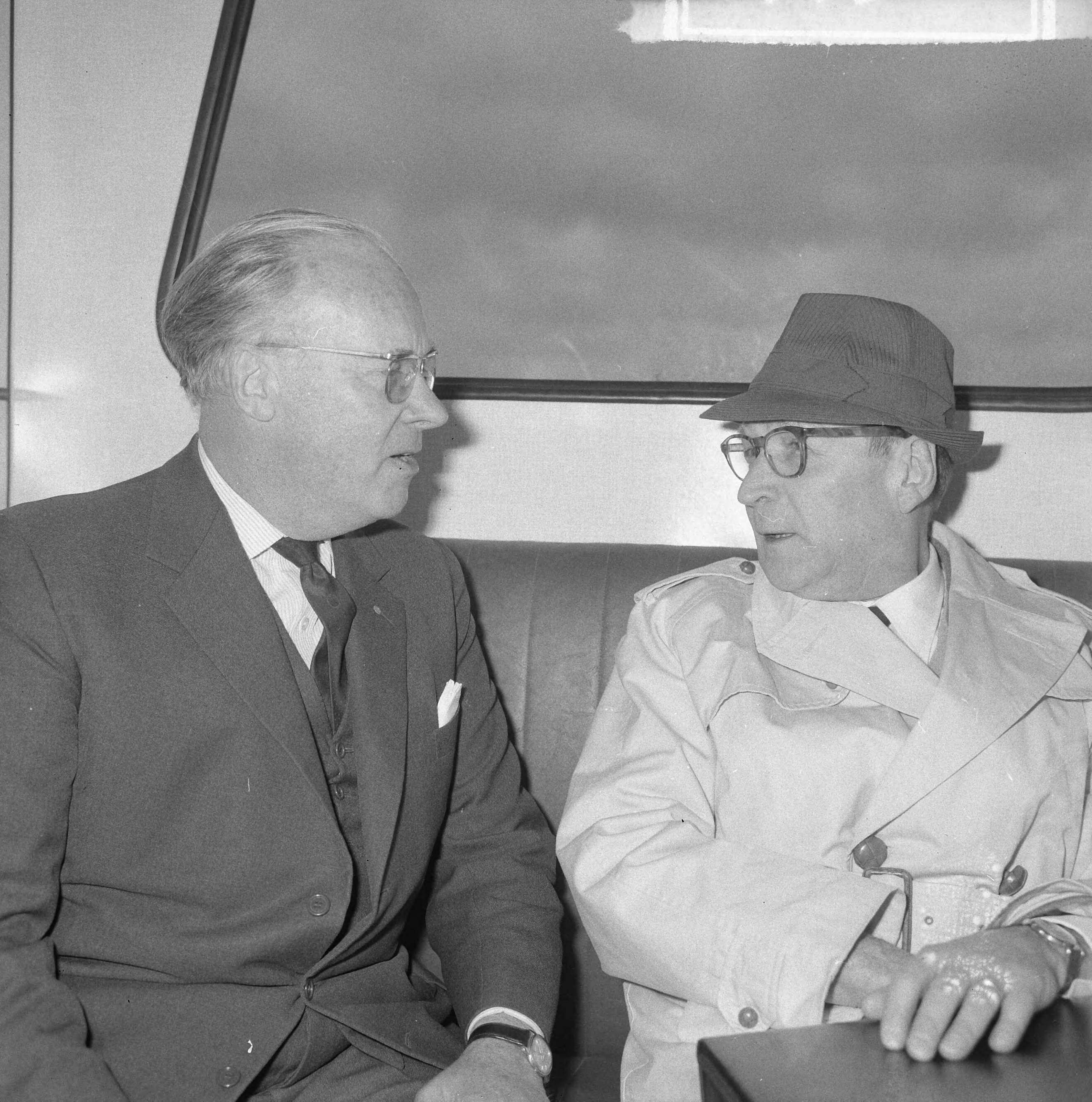 Fotocollectie Anefo — Aankomst Georges Simenon (auteur) op Schiphol, hier tijdens persconferentie. Hij kwam naar Nederland op uitnodiging van zijn Nederlandse uitgever A.W. Bruna (links) — Foto: Nijs, Jac. de / Anefo. Licentie: Set B: Rechtenvrij / Publiek Domein. Bron: Nationaal Archief. http://hdl.handle.net/10648/aaa68544-d0b4-102d-bcf8-003048976d84