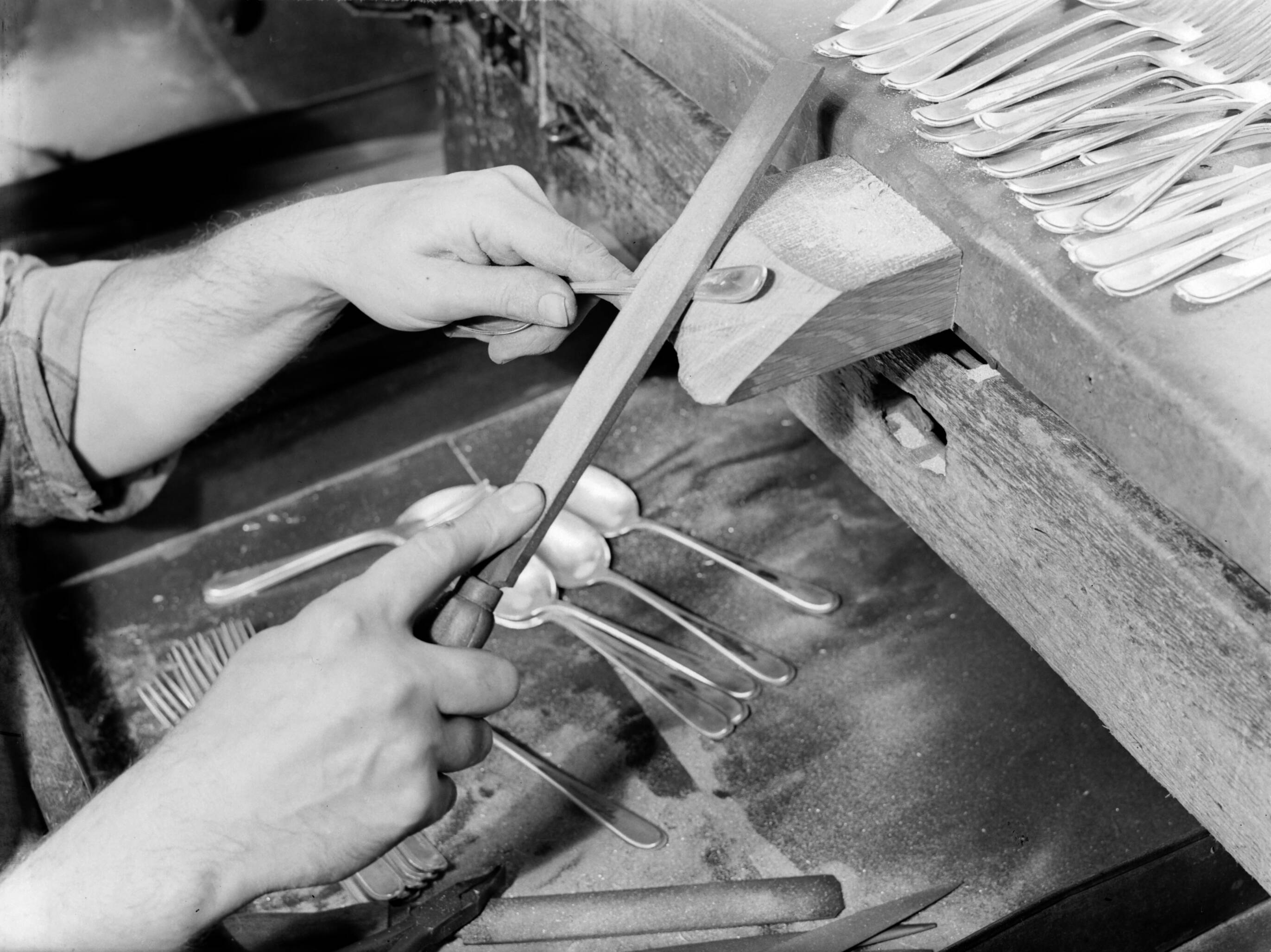 Productfoto's; zilverwerk — Lepels nabewerken met een vijl bij de fa. Gerritsen & Van Kempen in Zeist — Foto: Poll, Willem van de. Licentie: Set B: Rechtenvrij / Publiek Domein. Bron: Nationaal Archief. http://hdl.handle.net/10648/ae9e3a48-d0b4-102d-bcf8-003048976d84