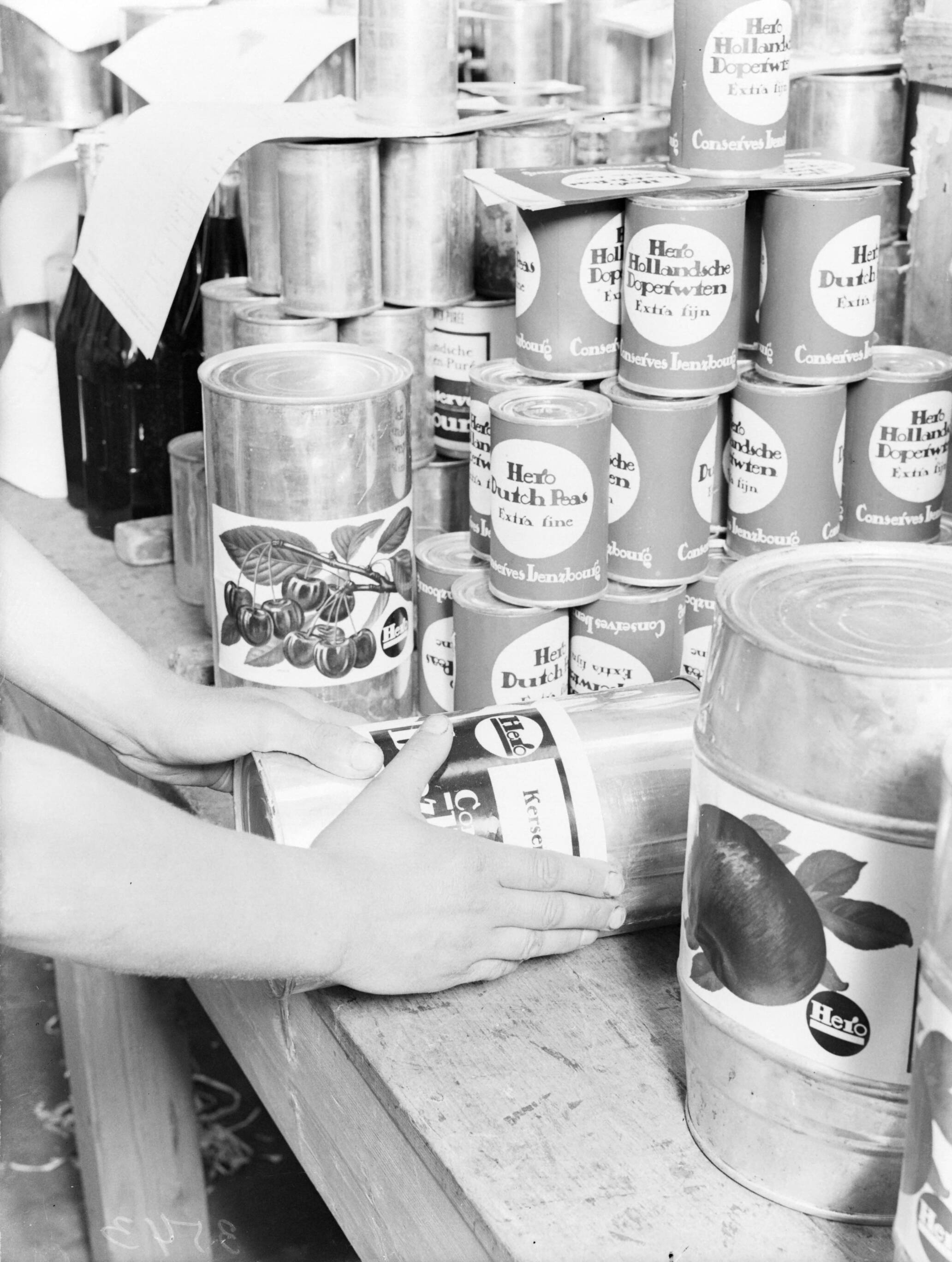 Reportage Hero-fabriek — Blikken worden van etiketten voorzien — Foto: Poll, Willem van de. Licentie: Set B: Rechtenvrij / Publiek Domein. Bron: Nationaal Archief. http://hdl.handle.net/10648/ae9a8970-d0b4-102d-bcf8-003048976d84