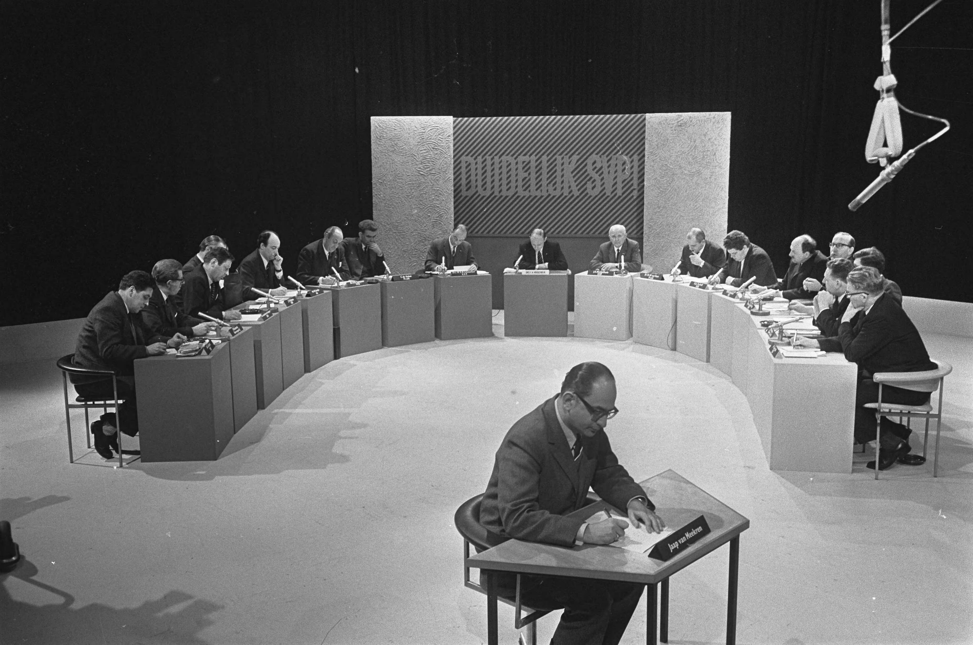 Fotocollectie Anefo — AVRO-TV, "Duidelijk svp" , zestien Nederlandse politici debatteren onder leiding van drs. F. A. Hoogendijk (midden) — Foto: Koch, Eric / Anefo. Licentie: Set B: Rechtenvrij / Publiek Domein. Bron: Nationaal Archief. http://hdl.handle.net/10648/ab34db96-d0b4-102d-bcf8-003048976d84