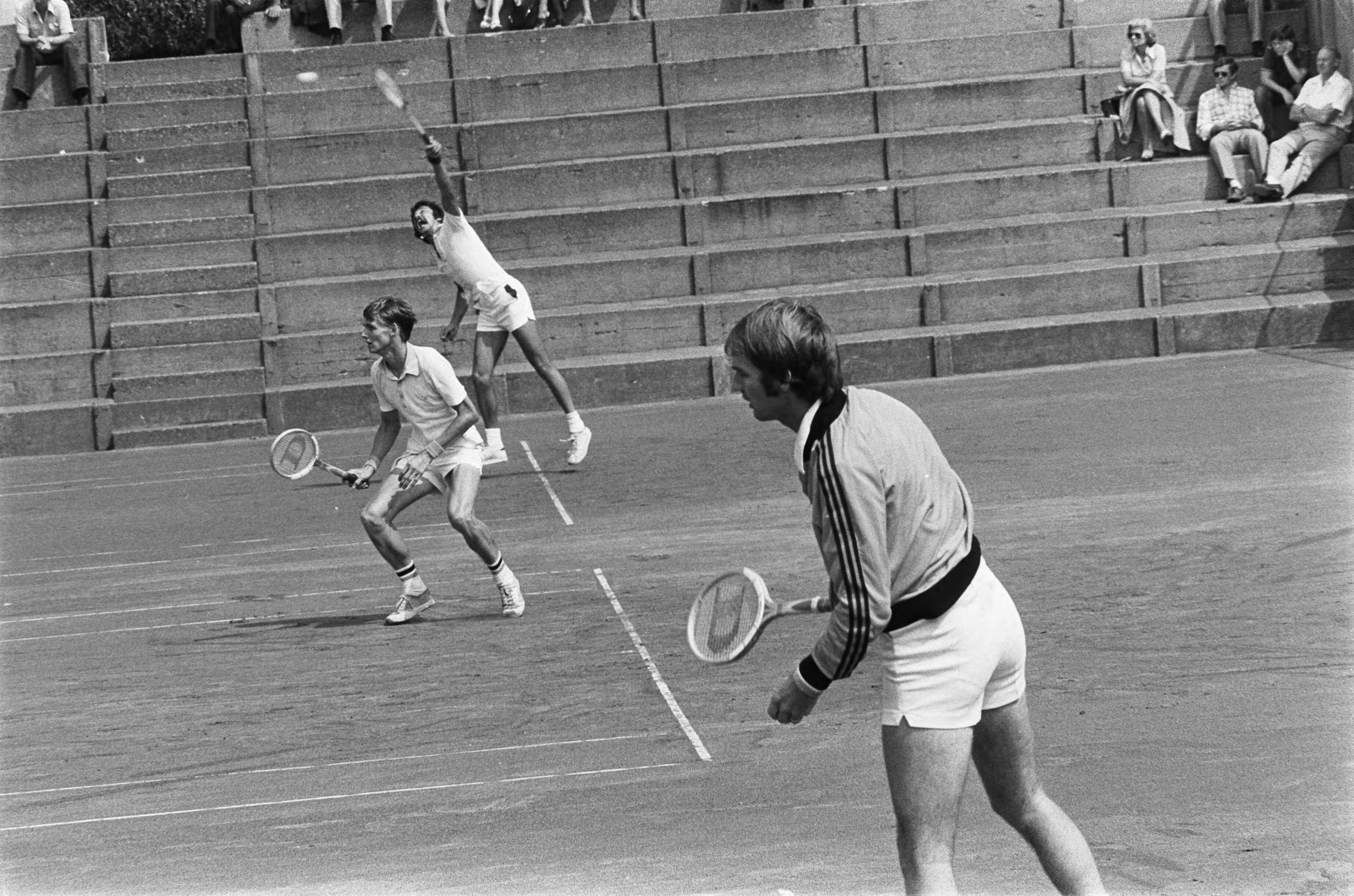 Nationale tenniskampioenschappen op de METS-tennisbanen 1975 — Sanders, voor, en Thung, achter, in twee naast elkaar gespeelde partijen — Foto: Mieremet, Rob / Anefo. Licentie: Set B: Rechtenvrij / Publiek Domein. Bron: Nationaal Archief. http://hdl.handle.net/10648/ac6f9e42-d0b4-102d-bcf8-003048976d84