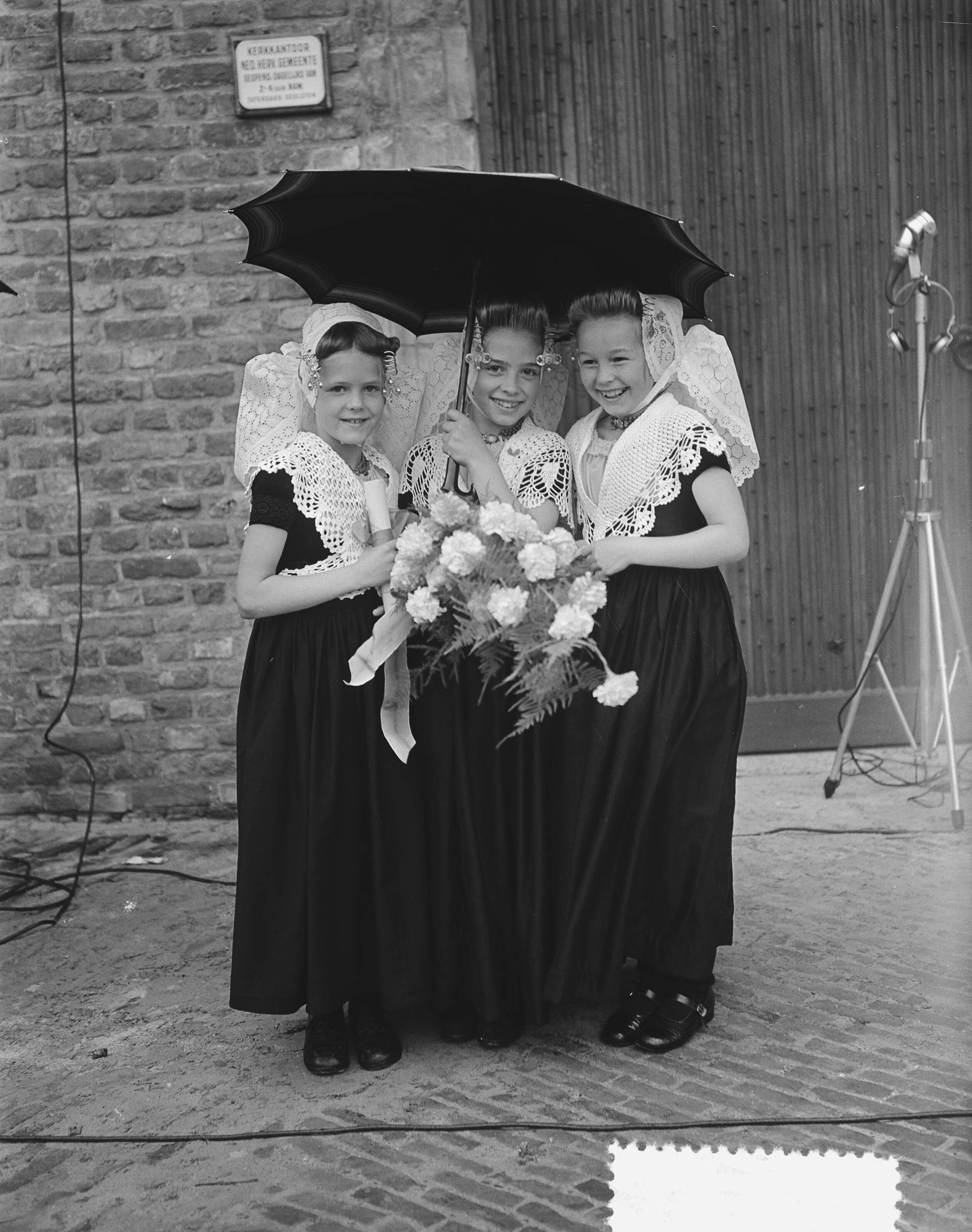 Koningin Juliana en prins Bernhard bezoeken Walcheren — Meisjes in Zeeuwse klederdracht wachten om koningin Juliana de bloemen te kunnen overhandigen — Foto: Bilsen, Joop van / Anefo. Licentie: Set B: Rechtenvrij / Publiek Domein. Bron: Nationaal Archief. http://hdl.handle.net/10648/a9245890-d0b4-102d-bcf8-003048976d84