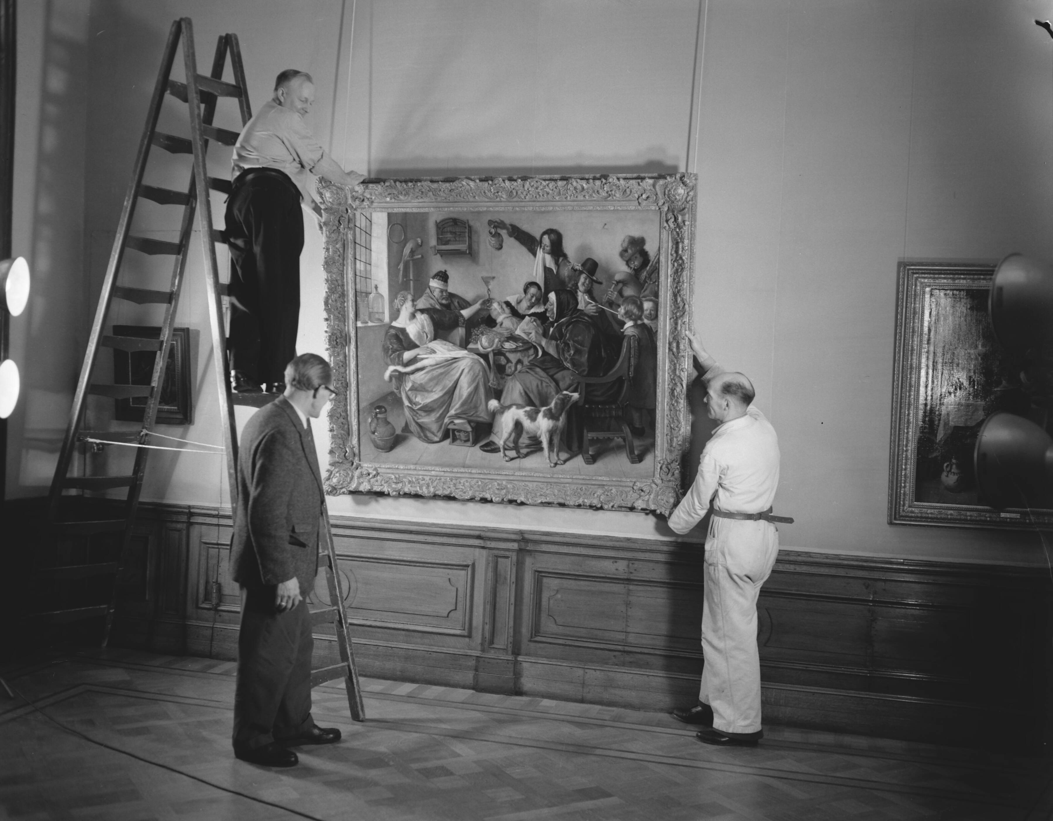 Fotocollectie Anefo — Voorbereidingen voor Jan Steen tentoonstelling in het Mauritshuis te Den Haag. Ophangen van het schilderij "Soo voer gesongen, soo na gepepen" — Foto: Behrens, Herbert F. / Anefo. Licentie: Set B: Rechtenvrij / Publiek Domein. Bron: Nationaal Archief. http://hdl.handle.net/10648/a98a64a0-d0b4-102d-bcf8-003048976d84