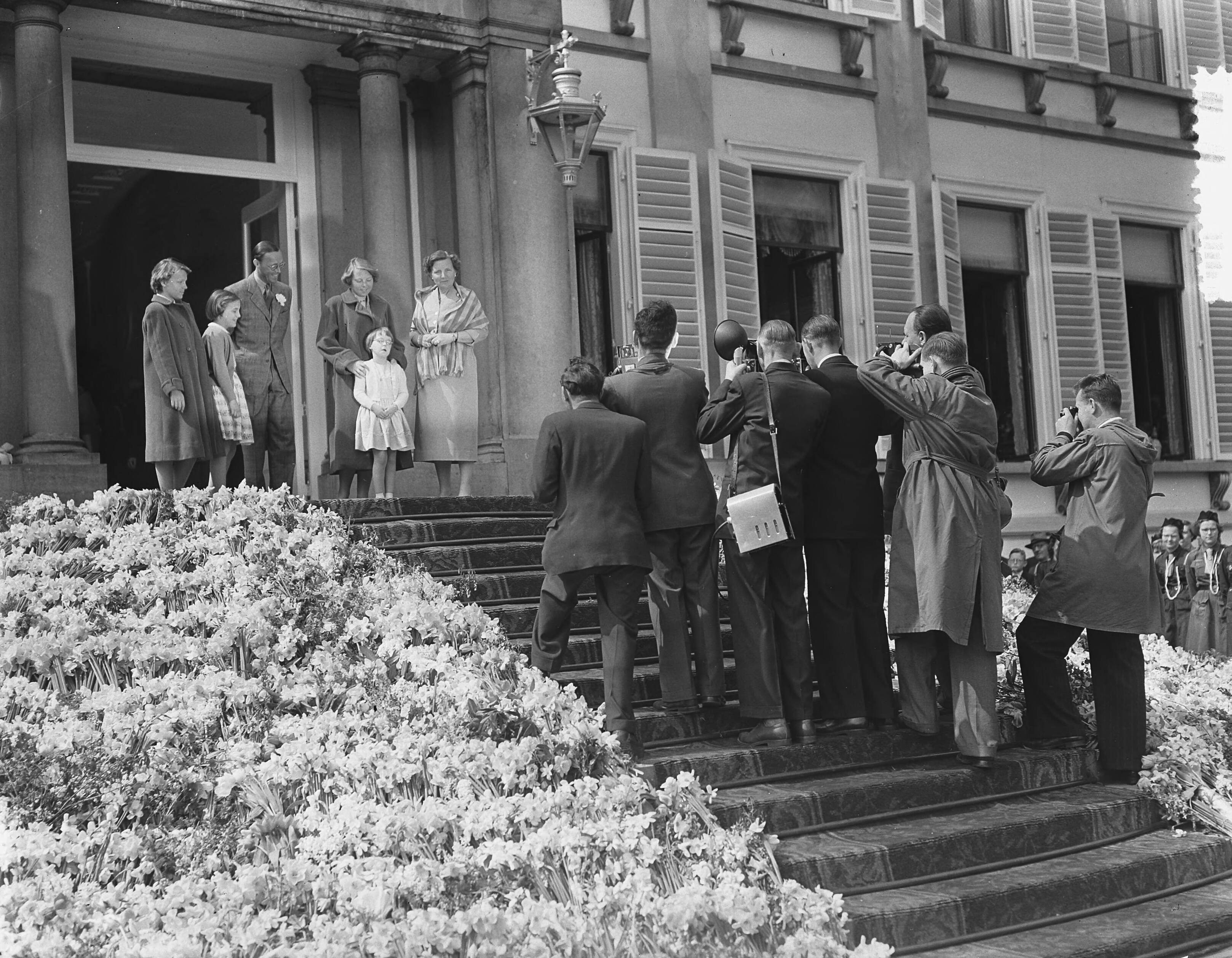 Koninginnedag 1954 — Koninginnedag. Defilé op paleis Soestdijk. Bordes met koninklijke familie. Fotografen maken een opname van het koninklijk gezin — Foto: Bilsen, Joop van / Anefo. Licentie: Set B: Rechtenvrij / Publiek Domein. Bron: Nationaal Archief. http://hdl.handle.net/10648/a92137b4-d0b4-102d-bcf8-003048976d84