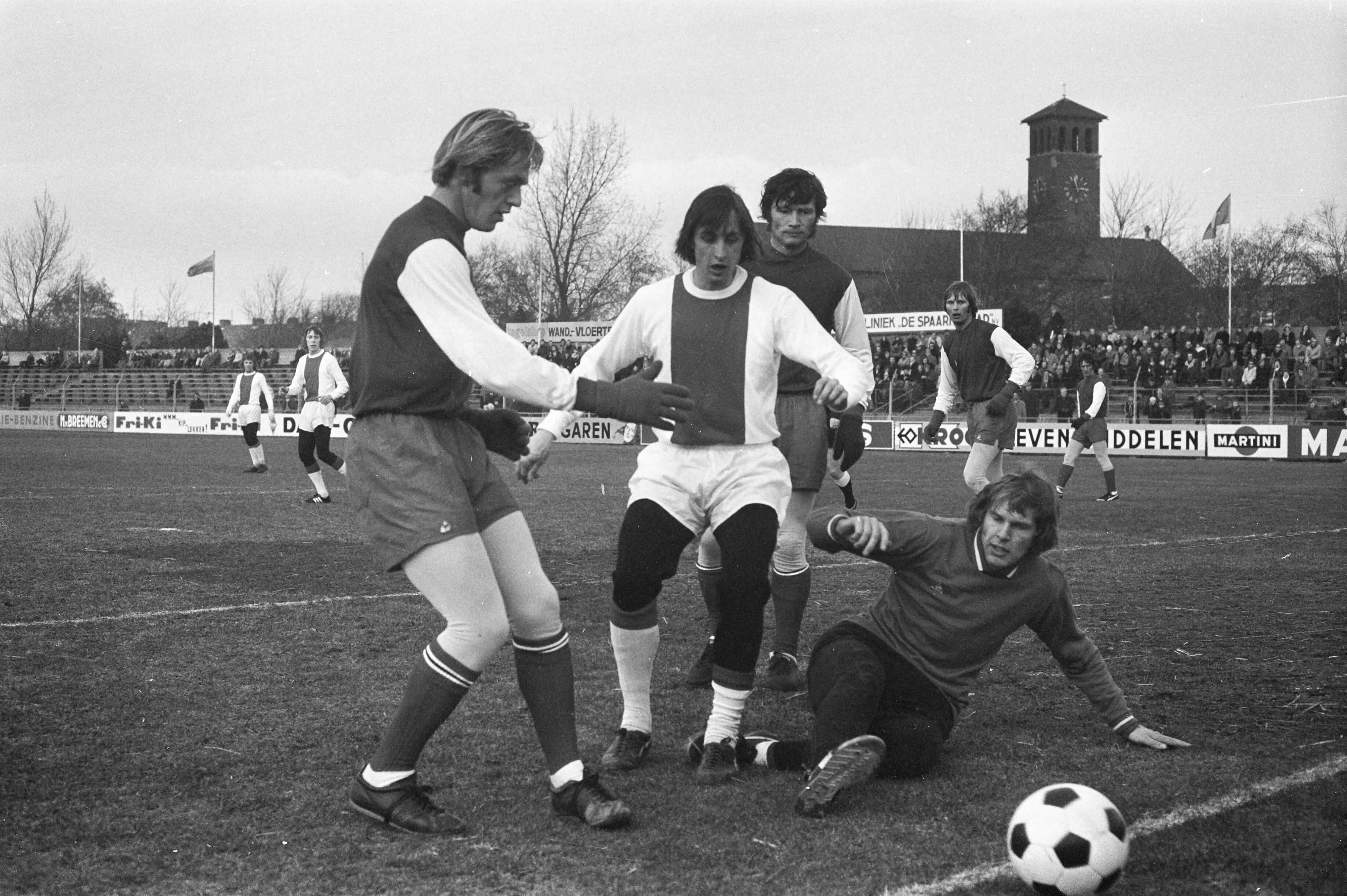Fotocollectie Anefo — Vriendschappelijke wedstrijd Haarlem tegen Ajax, Cruijff (midden) in maillot in actie, op de grond keeper Polderma — Foto: Peters, Hans / Anefo. Licentie: Set B: Rechtenvrij / Publiek Domein. Bron: Nationaal Archief. http://hdl.handle.net/10648/abdf7d9e-d0b4-102d-bcf8-003048976d84