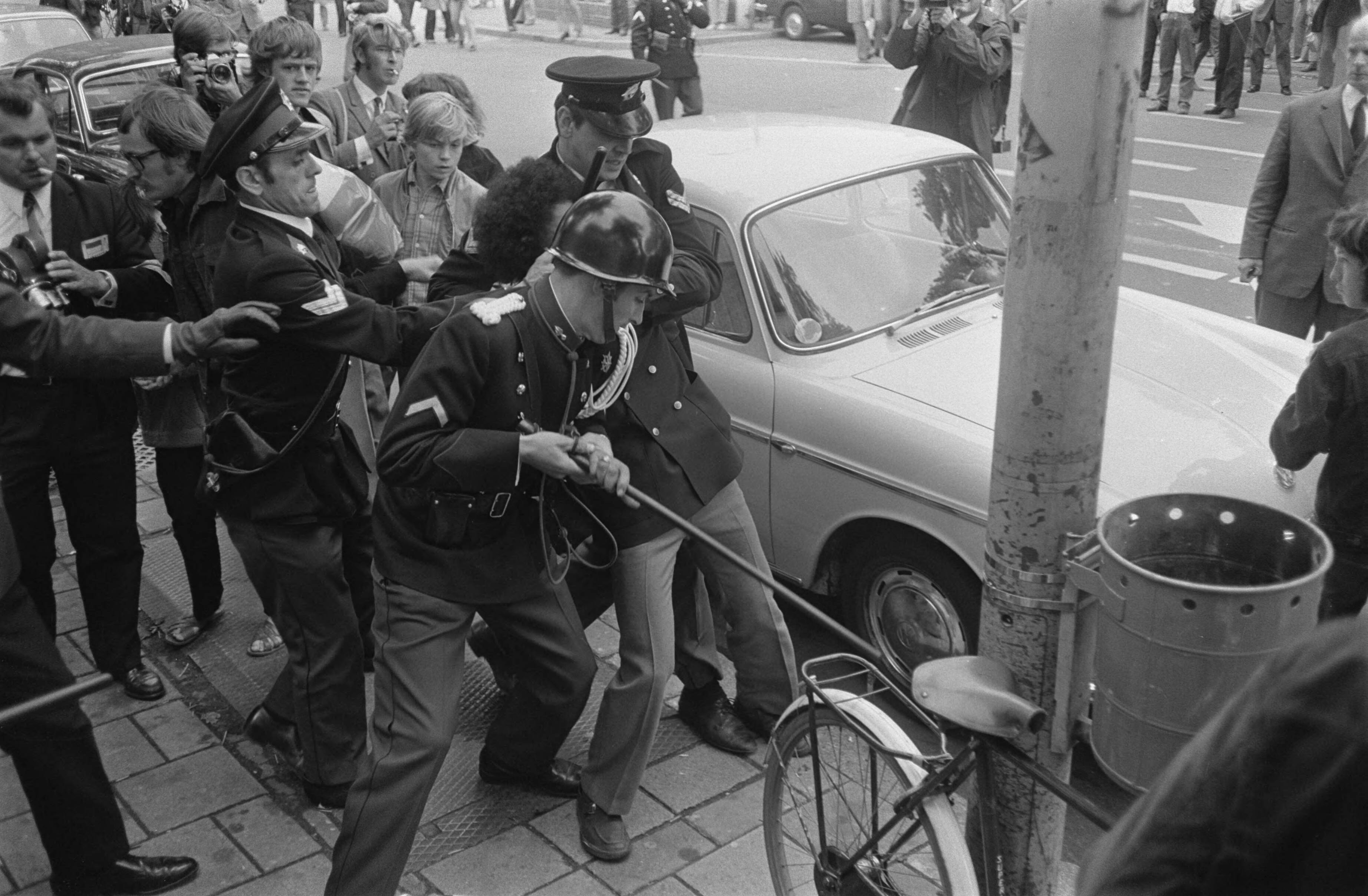 Fotocollectie Anefo — Demonstrerende Zuid-Molukkers worden door politie weggestuurd op Buitenhof, Den Haag — Foto: Koch, Eric / Anefo. Licentie: Set B: Rechtenvrij / Publiek Domein. Bron: Nationaal Archief. http://hdl.handle.net/10648/aba22f7a-d0b4-102d-bcf8-003048976d84
