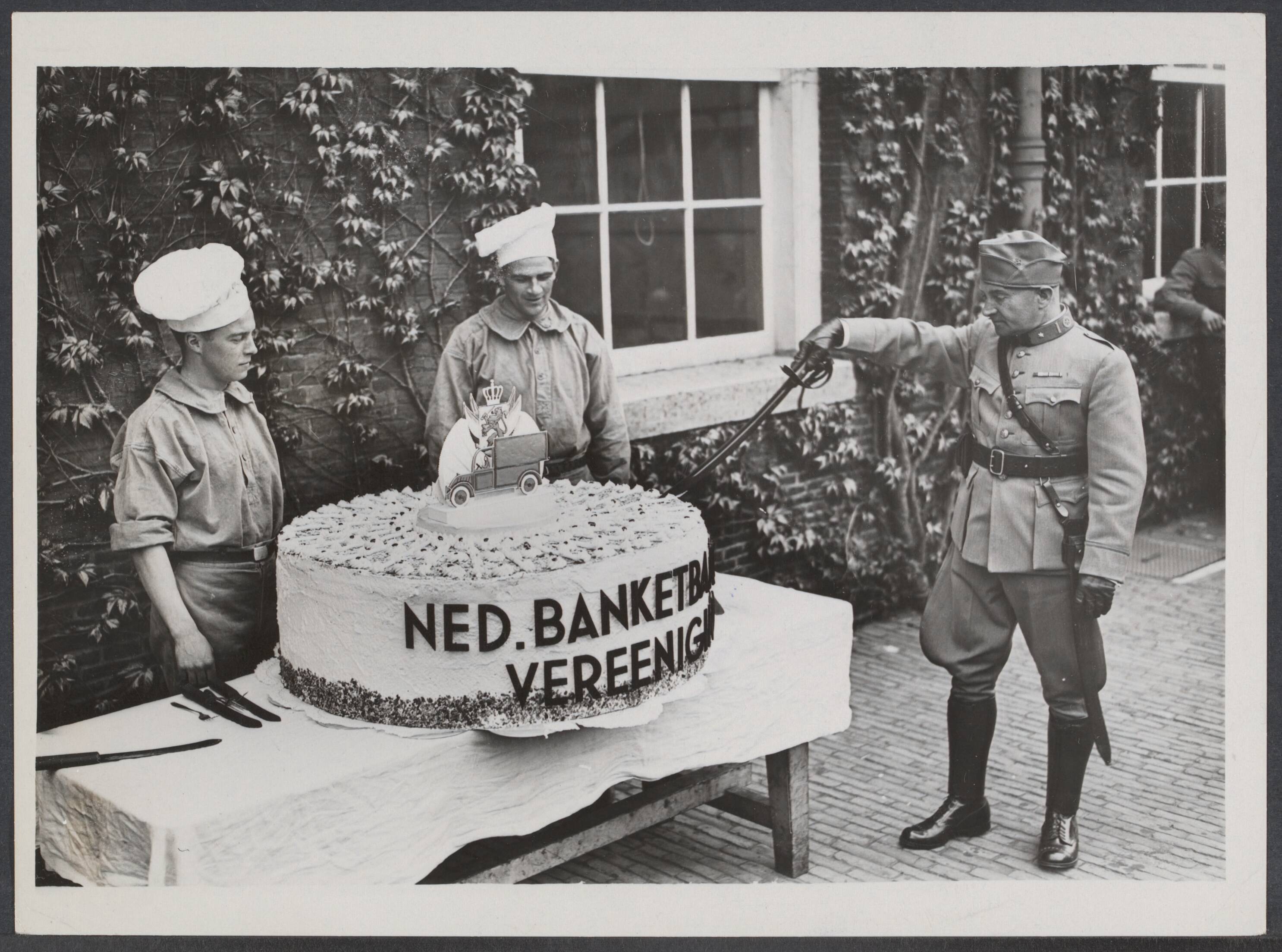 Mobilisatie; voorgeschiedenis W.O.II enz. - Nederland — Ergens in Nederland. Aan een kazerne werd een taart van 1 meter middellijn uitgereikt, werk met veel ceremonie door de commandant werd aangesneden ter ere van moederdag — Foto: N.V. Vereenigde Fotobureaux. Licentie: Set B: Rechtenvrij / Publiek Domein. Bron: Nationaal Archief. http://hdl.handle.net/10648/5cec9276-961f-42d1-8fd1-0866db362097