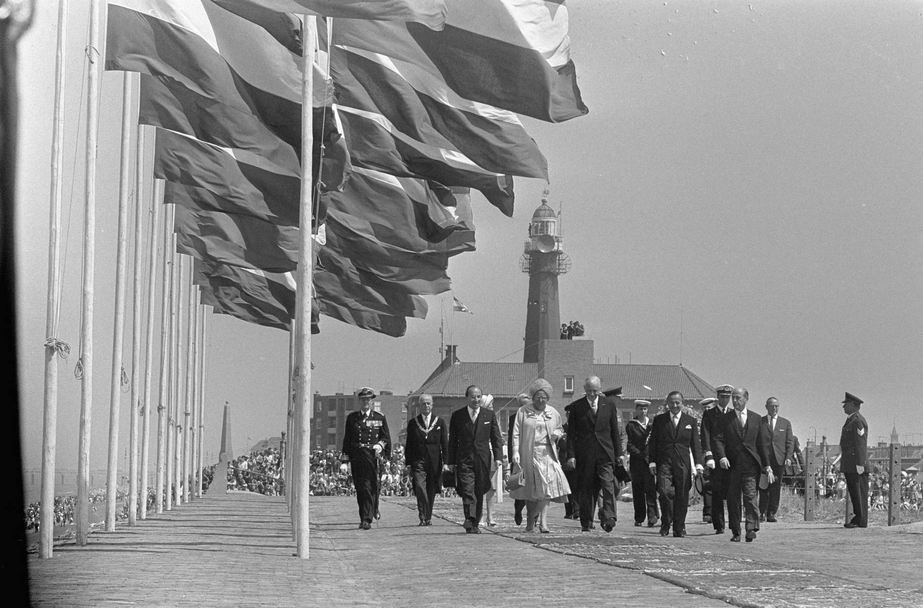 Koningin Juliana onthult het Marinemonument te Scheveningen — Het gezelschap loopt naar het monument — Foto: Koch, Eric / Anefo. Licentie: Set B: Rechtenvrij / Publiek Domein. Bron: Nationaal Archief. http://hdl.handle.net/10648/aaee793a-d0b4-102d-bcf8-003048976d84